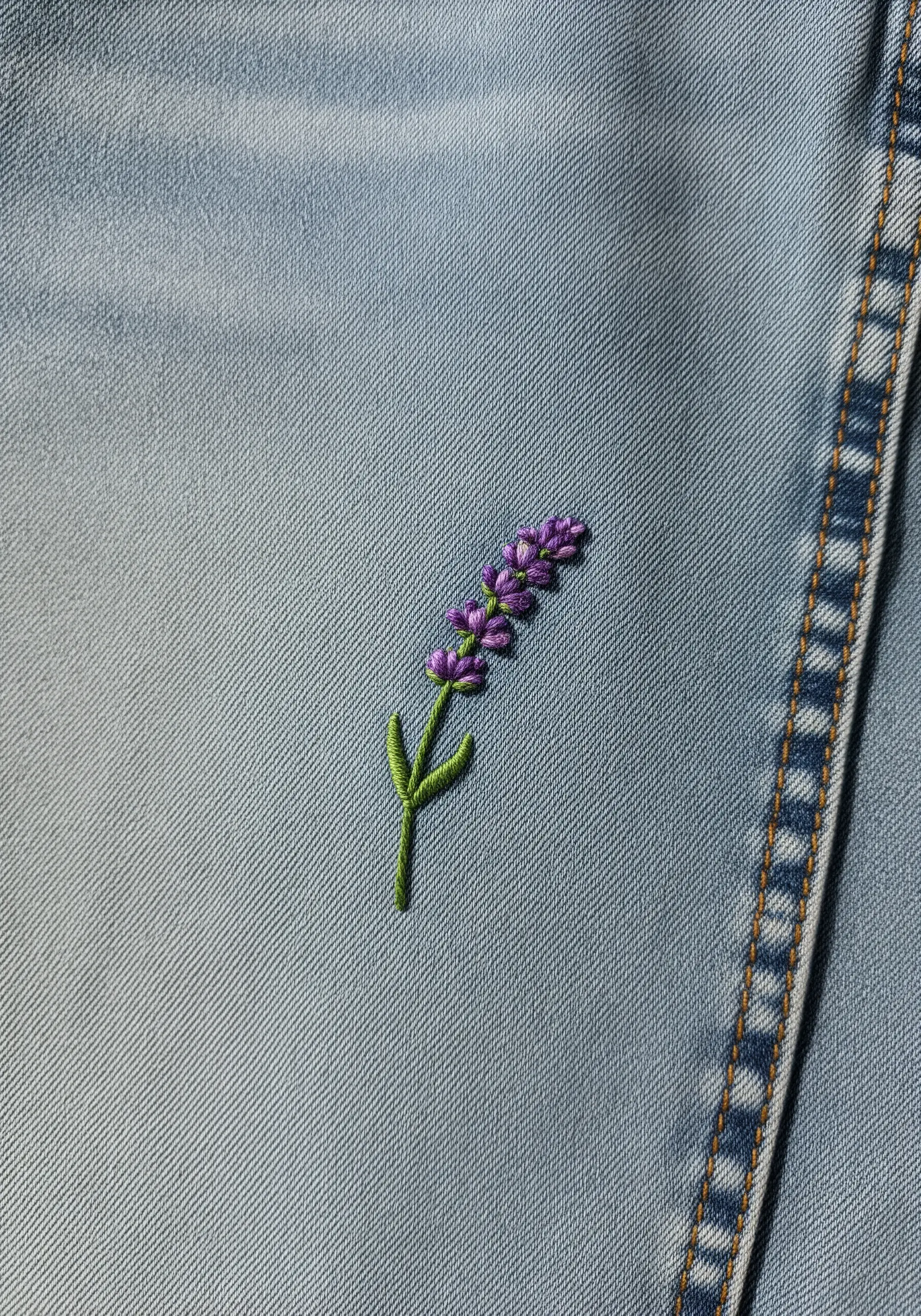 A delicate sprig of lavender embroidered with purple French knots on light-wash denim.