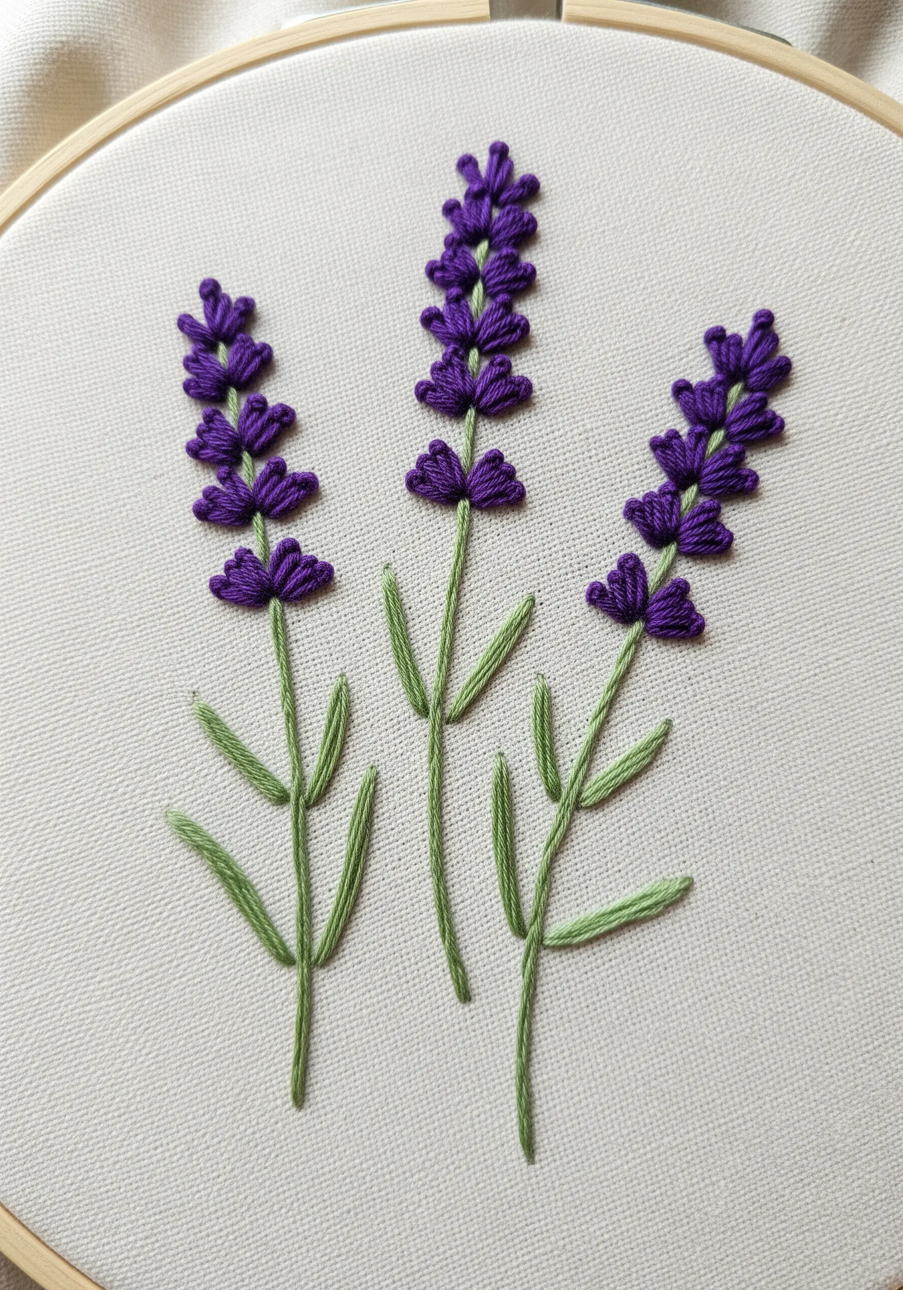 Three lavender stalks embroidered with purple French knots and green stem stitch.