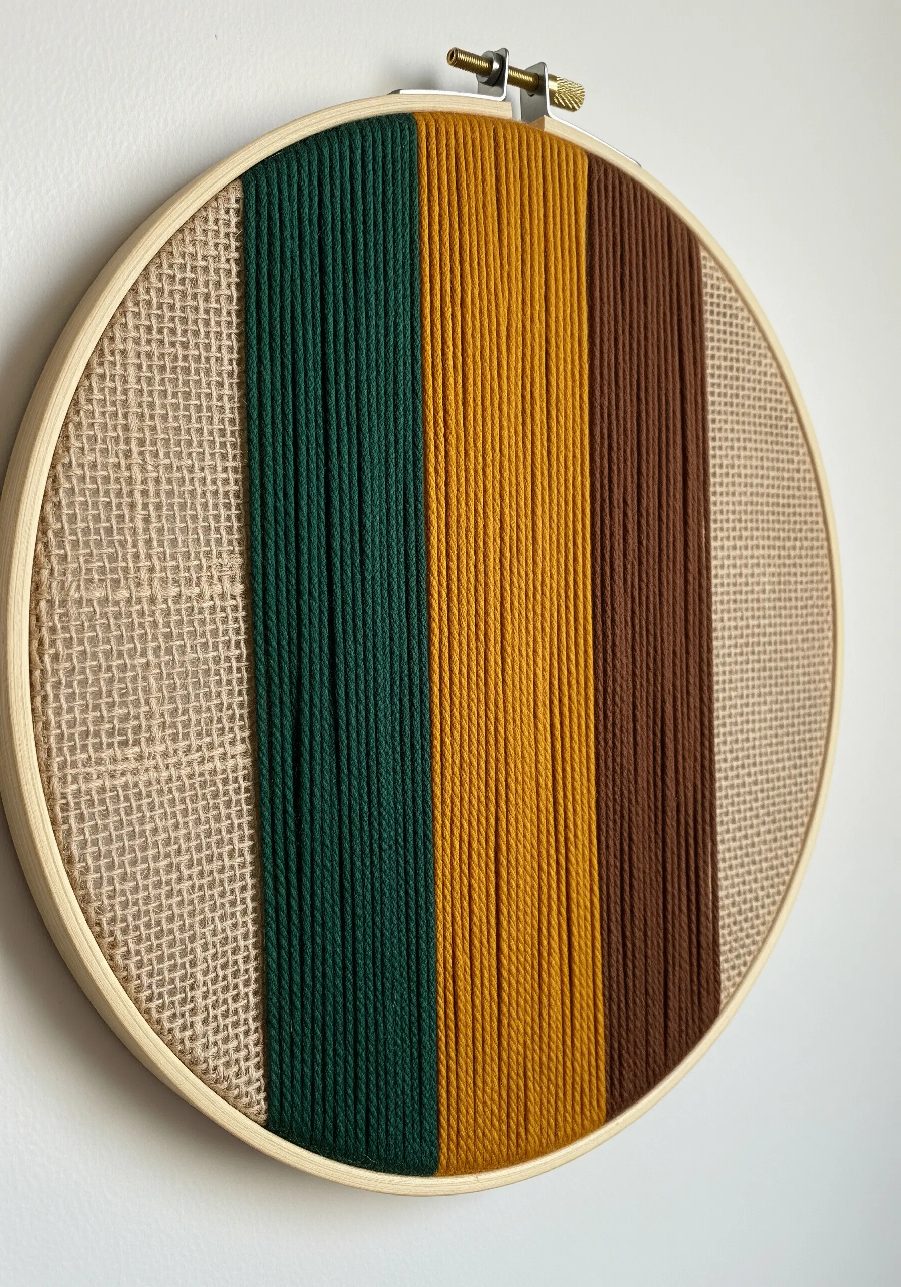A color-blocked hoop combining a burlap panel with wrapped yarn in earthy tones.