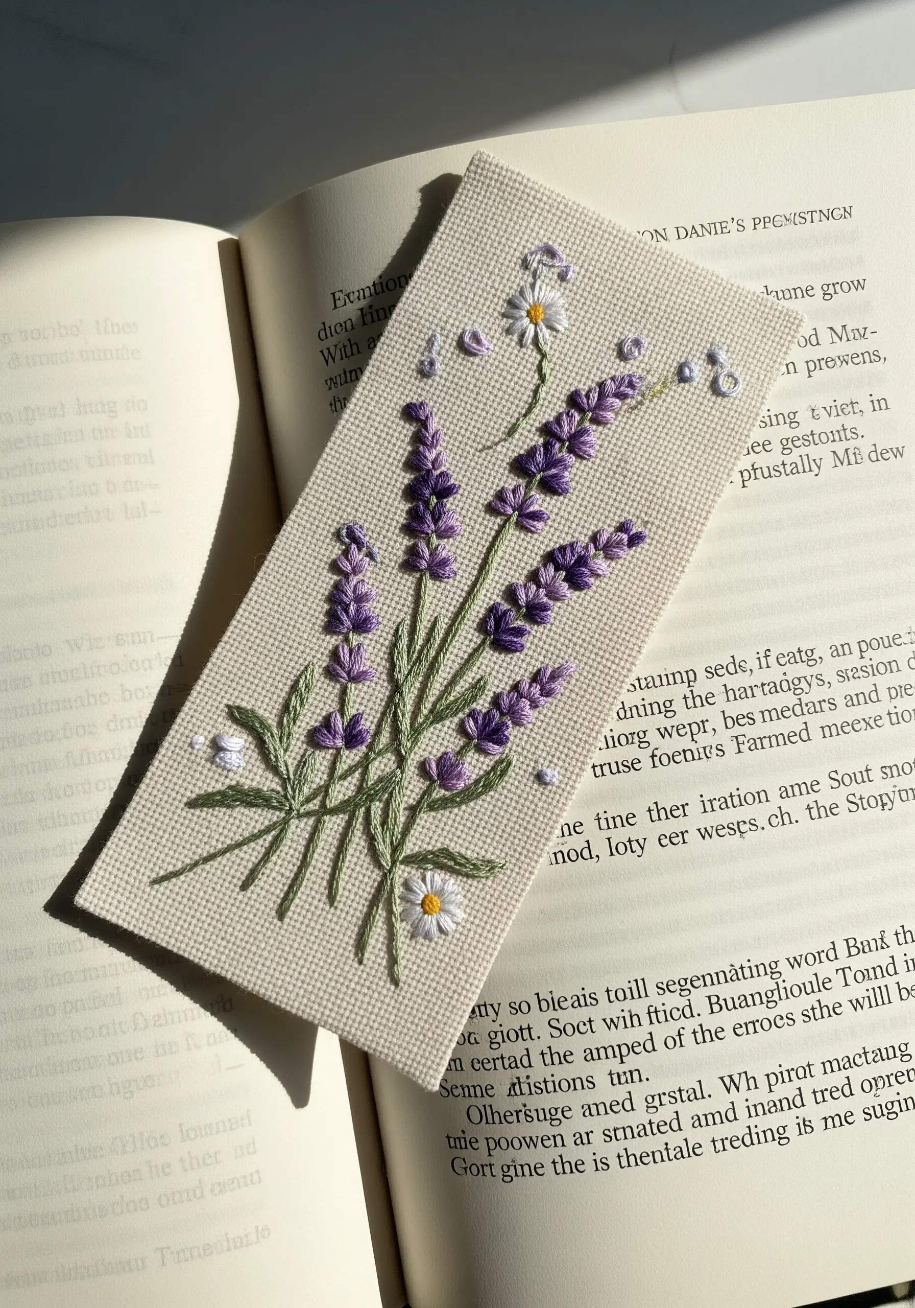 An embroidered bookmark with a delicate bouquet of lavender and daisies on cream Aida cloth.