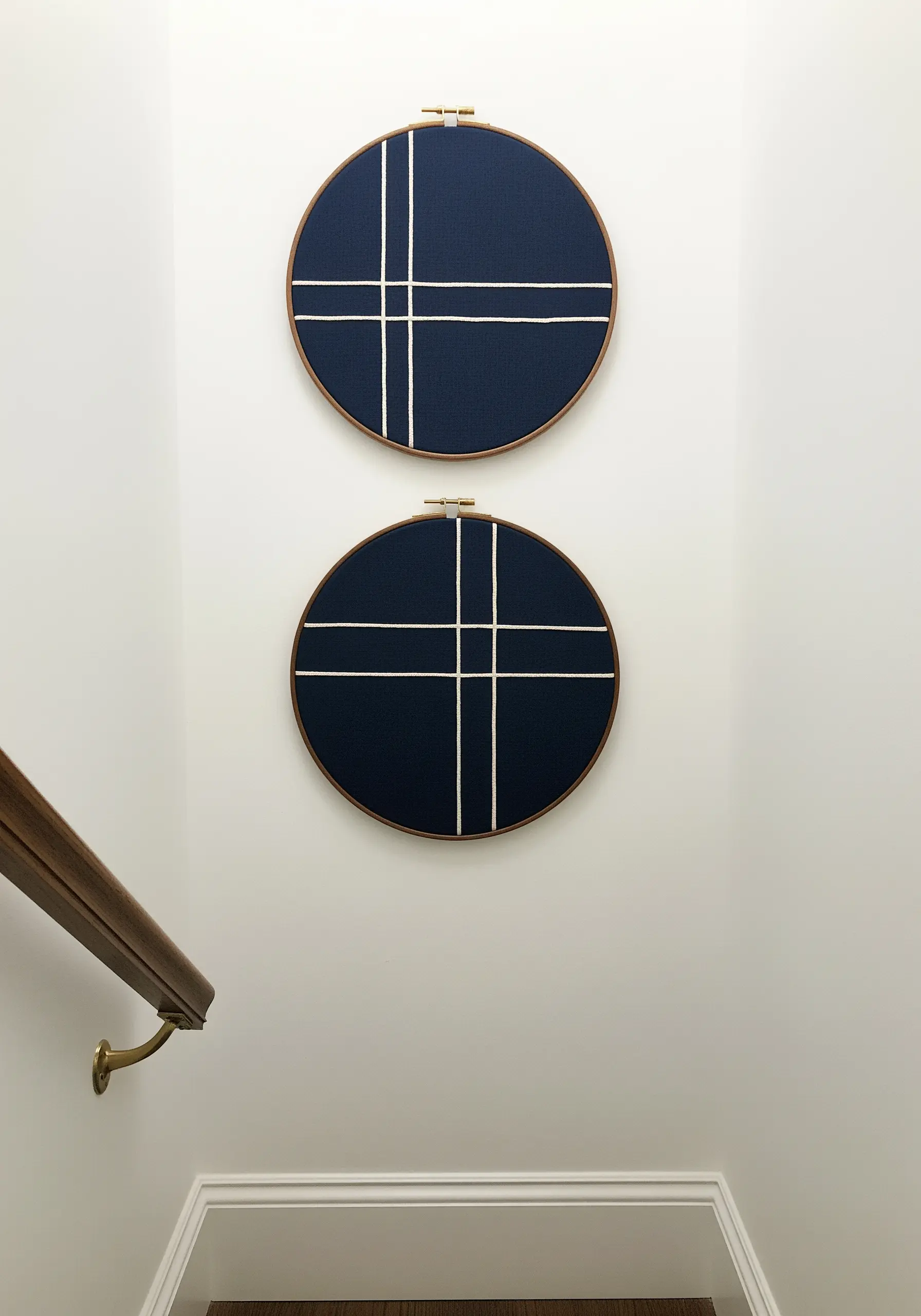 Two hoops with abstract white grid lines embroidered on navy blue fabric.