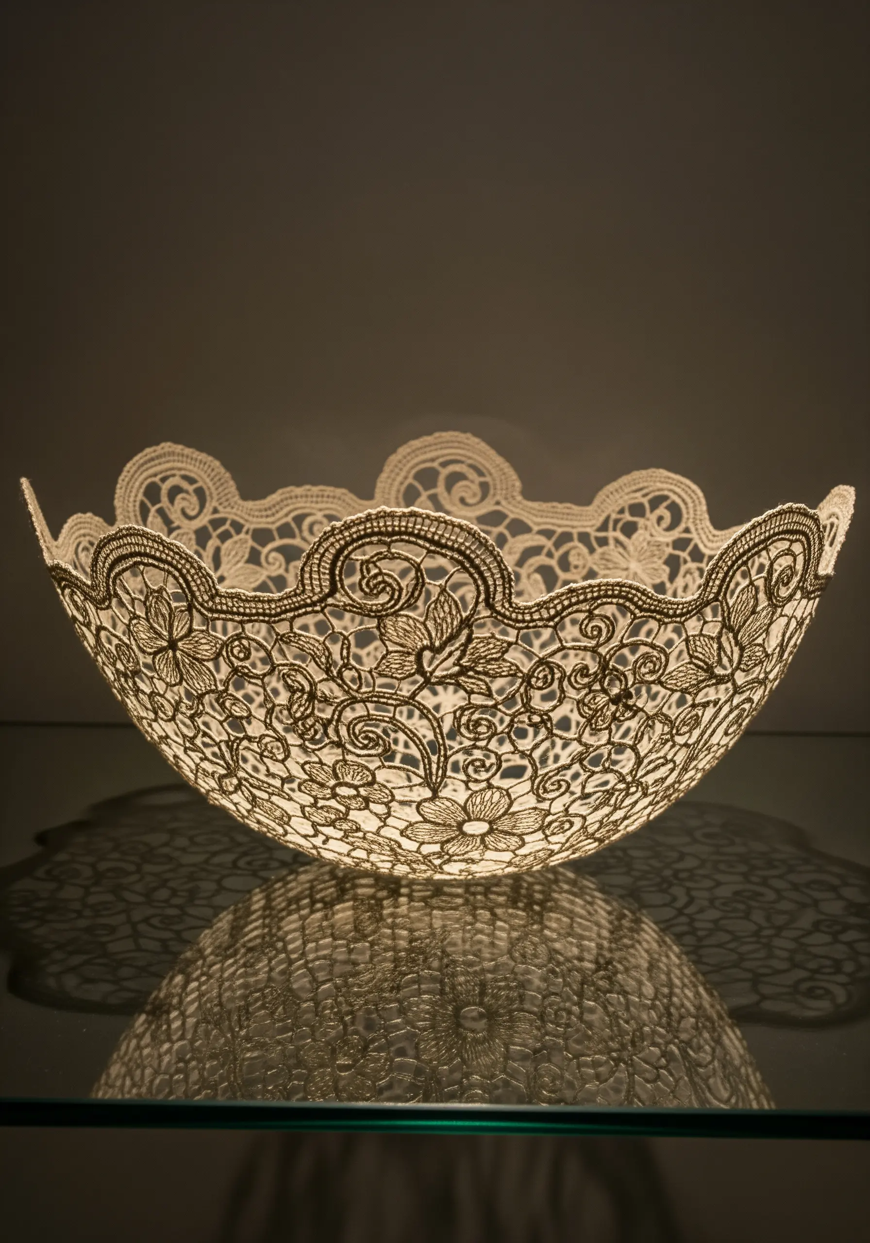 A delicate, sculptural bowl made entirely of freestanding white lace, lit from within.