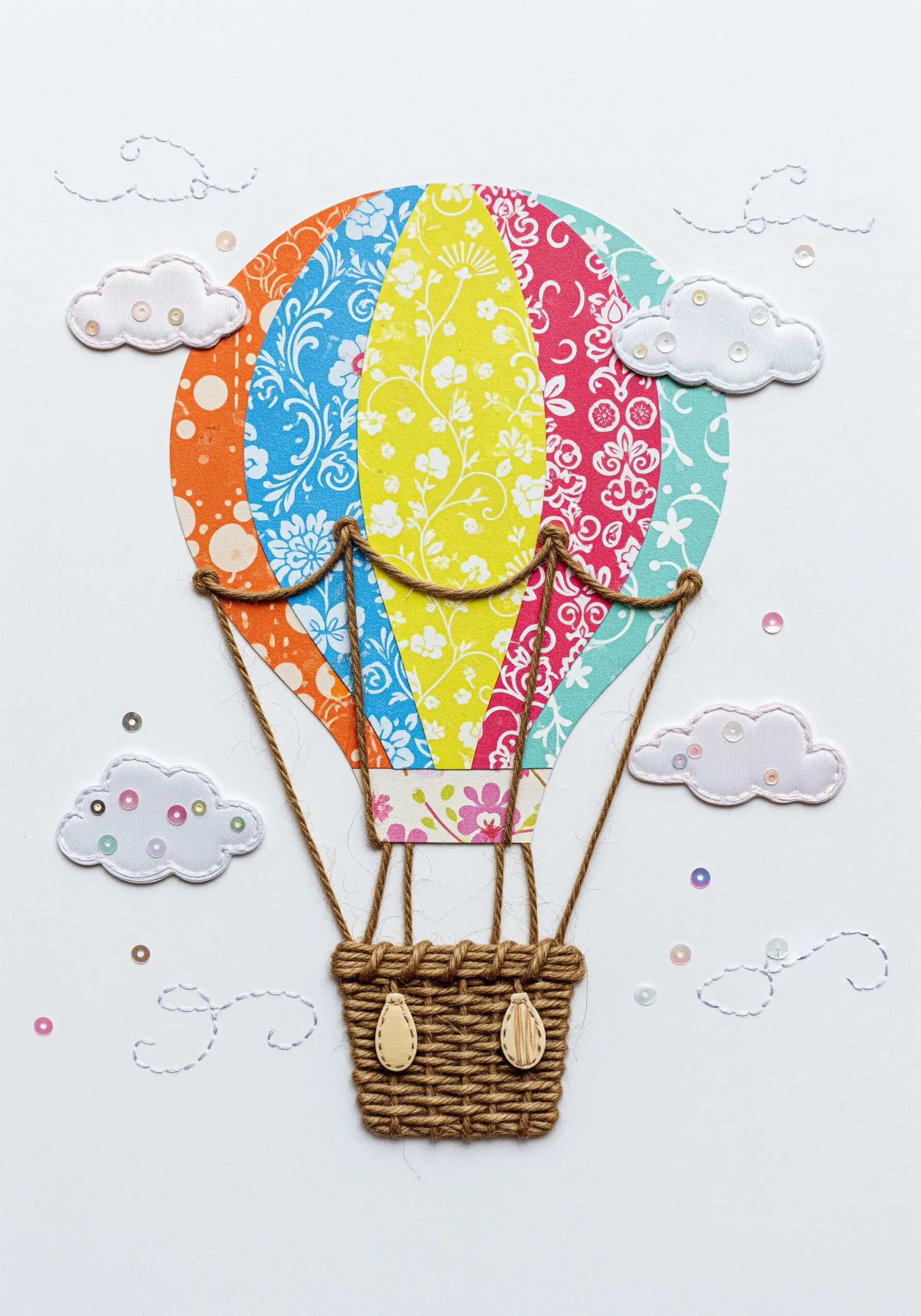 A hot air balloon collage made from colorful patterned paper with a woven thread basket.