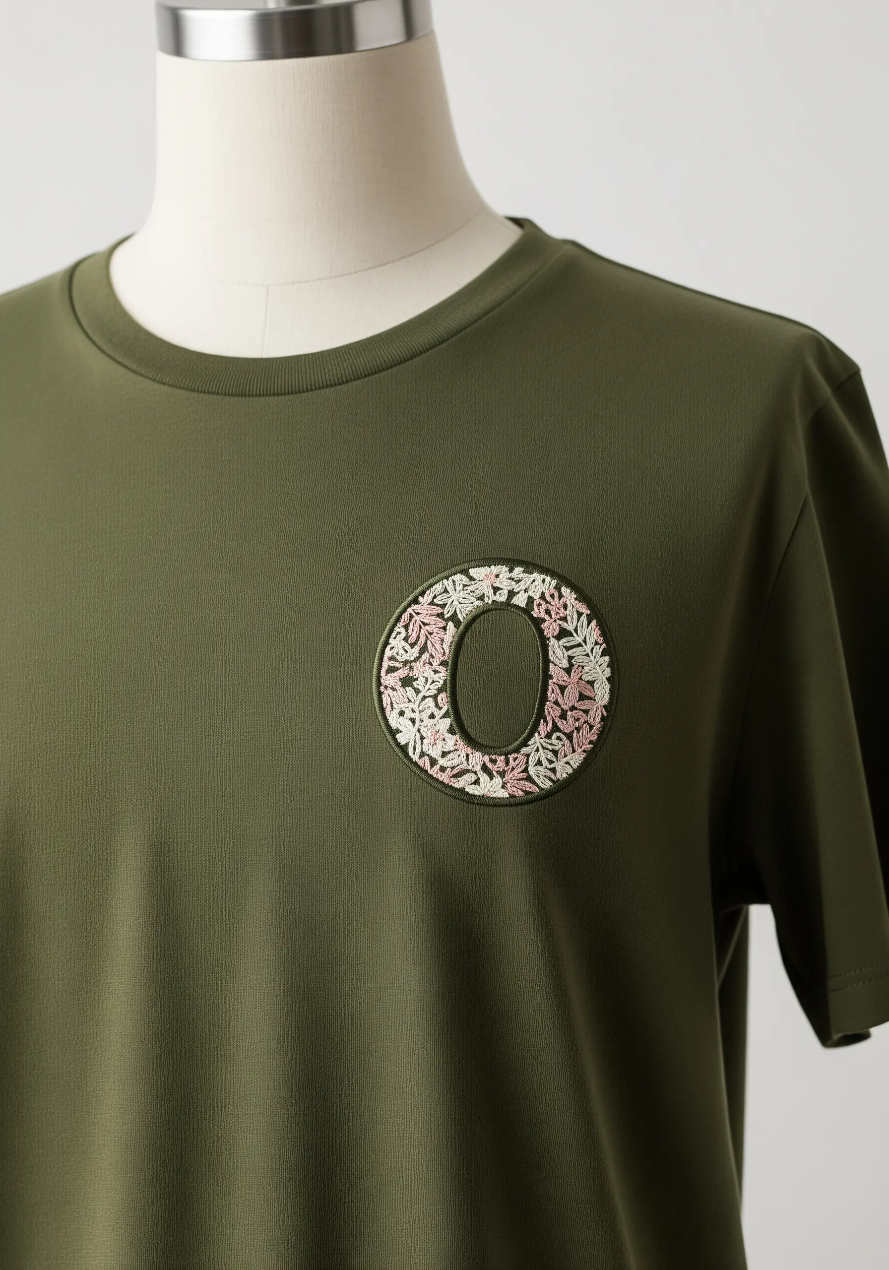 The letter 'O' defined by a negative space center and a floral-filled embroidered border.