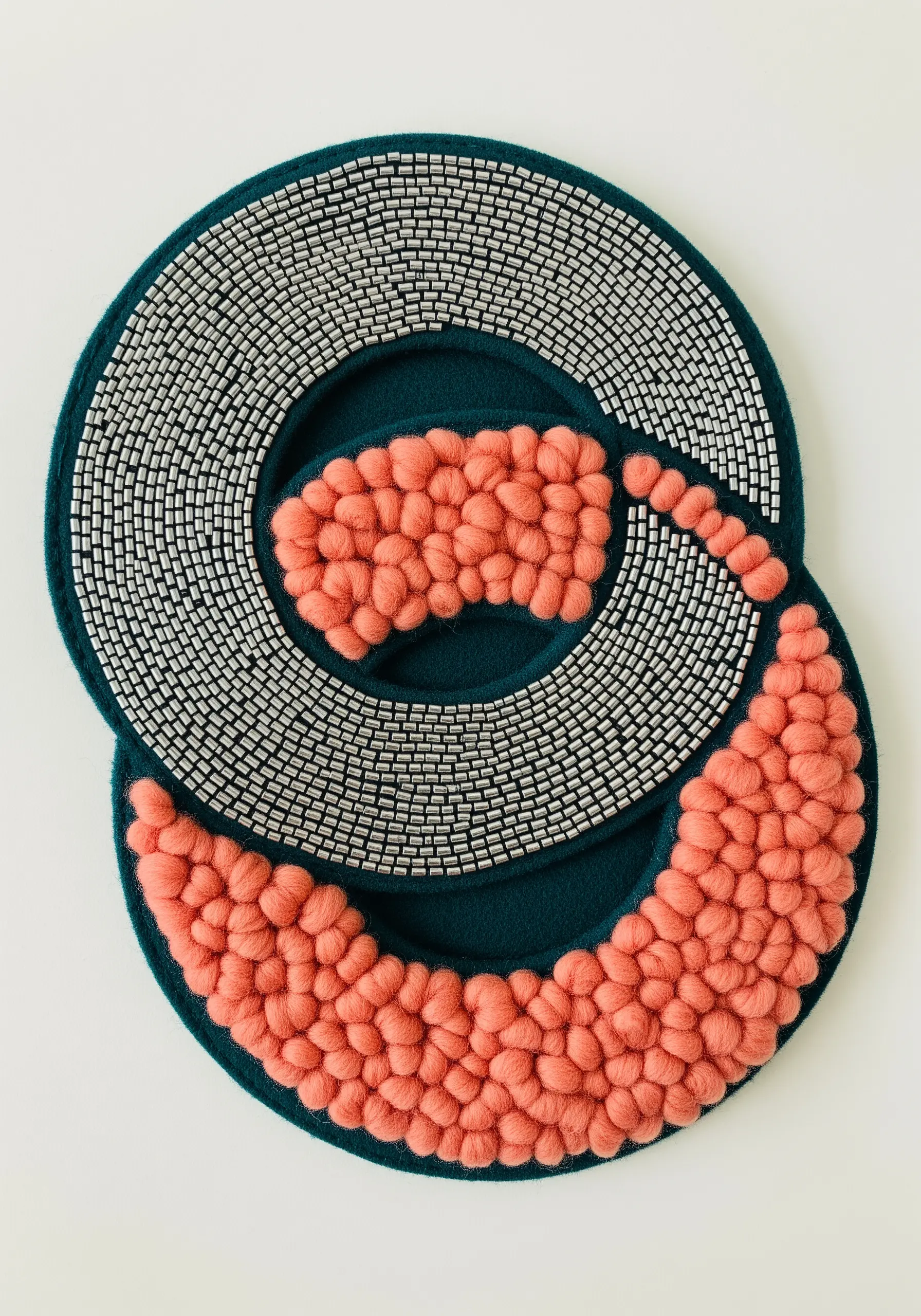Abstract textile art combining rows of silver seed beads with soft, fluffy pink wool.