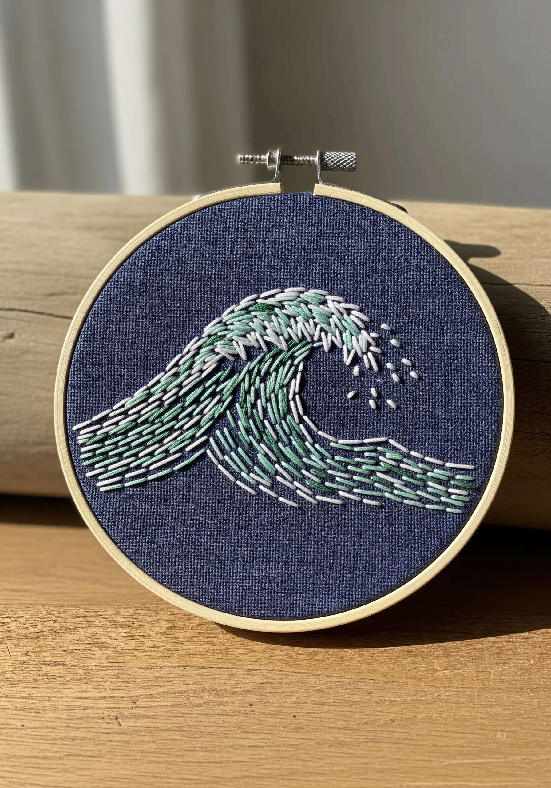 An embroidered ocean wave made of expressive straight stitches in shades of green and white.
