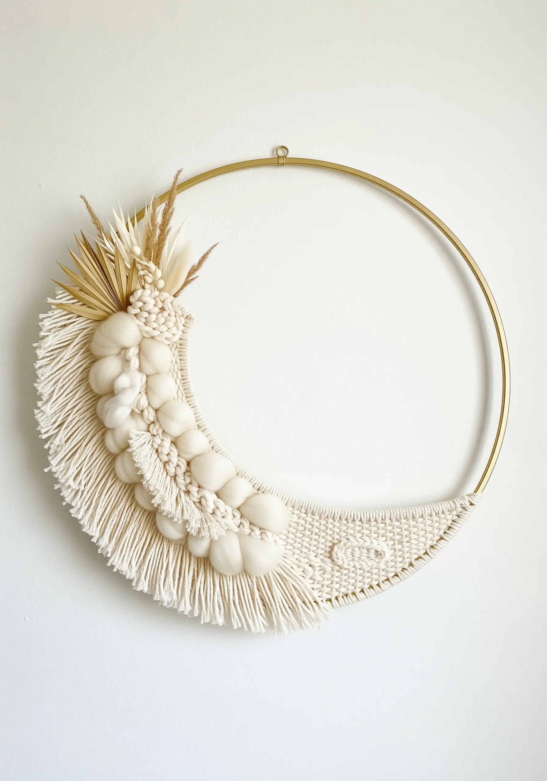 A crescent-shaped macrame weaving on a brass hoop, accented with dried botanicals.