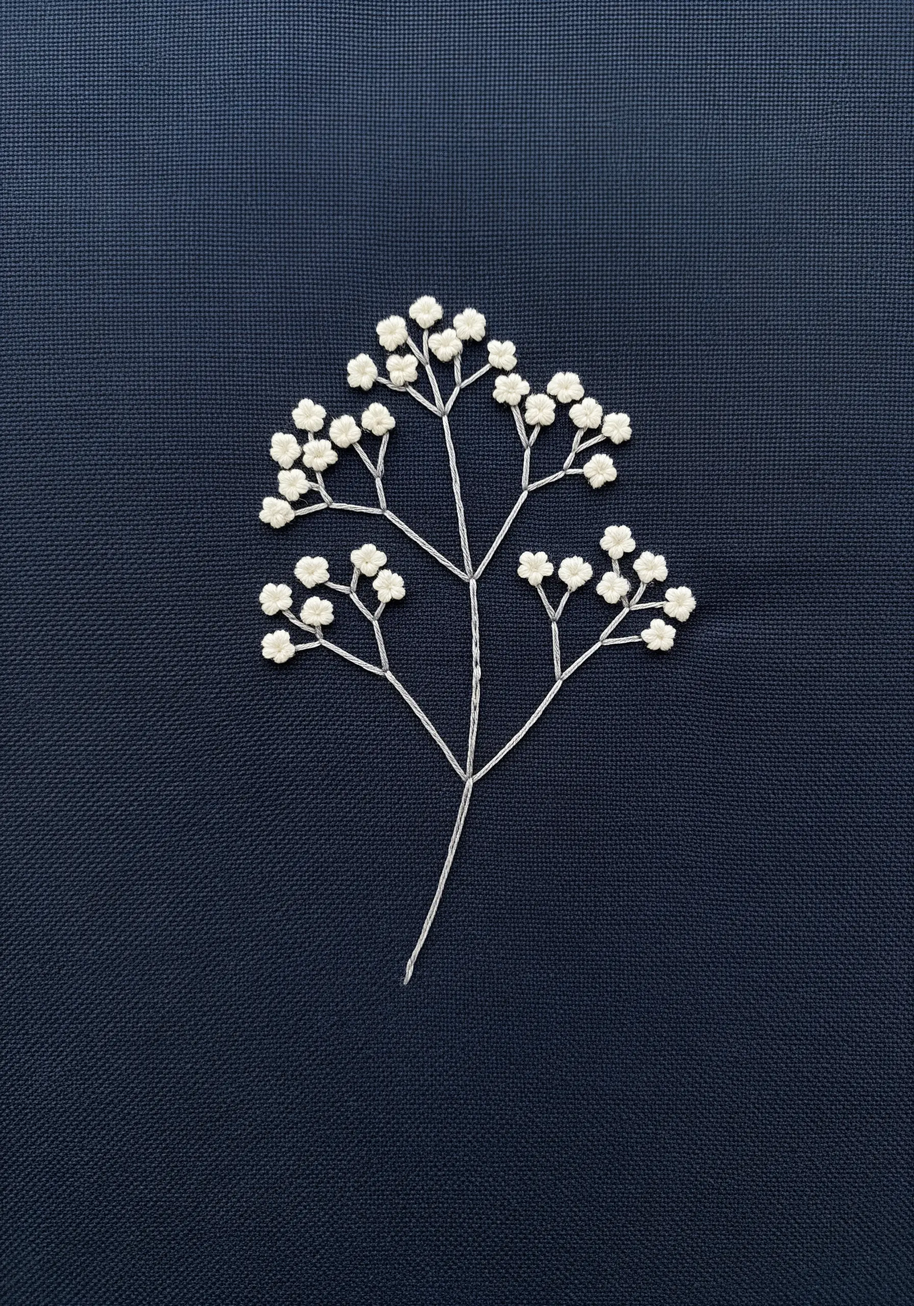 Delicate white baby's breath embroidered with fine thread on dark navy fabric.