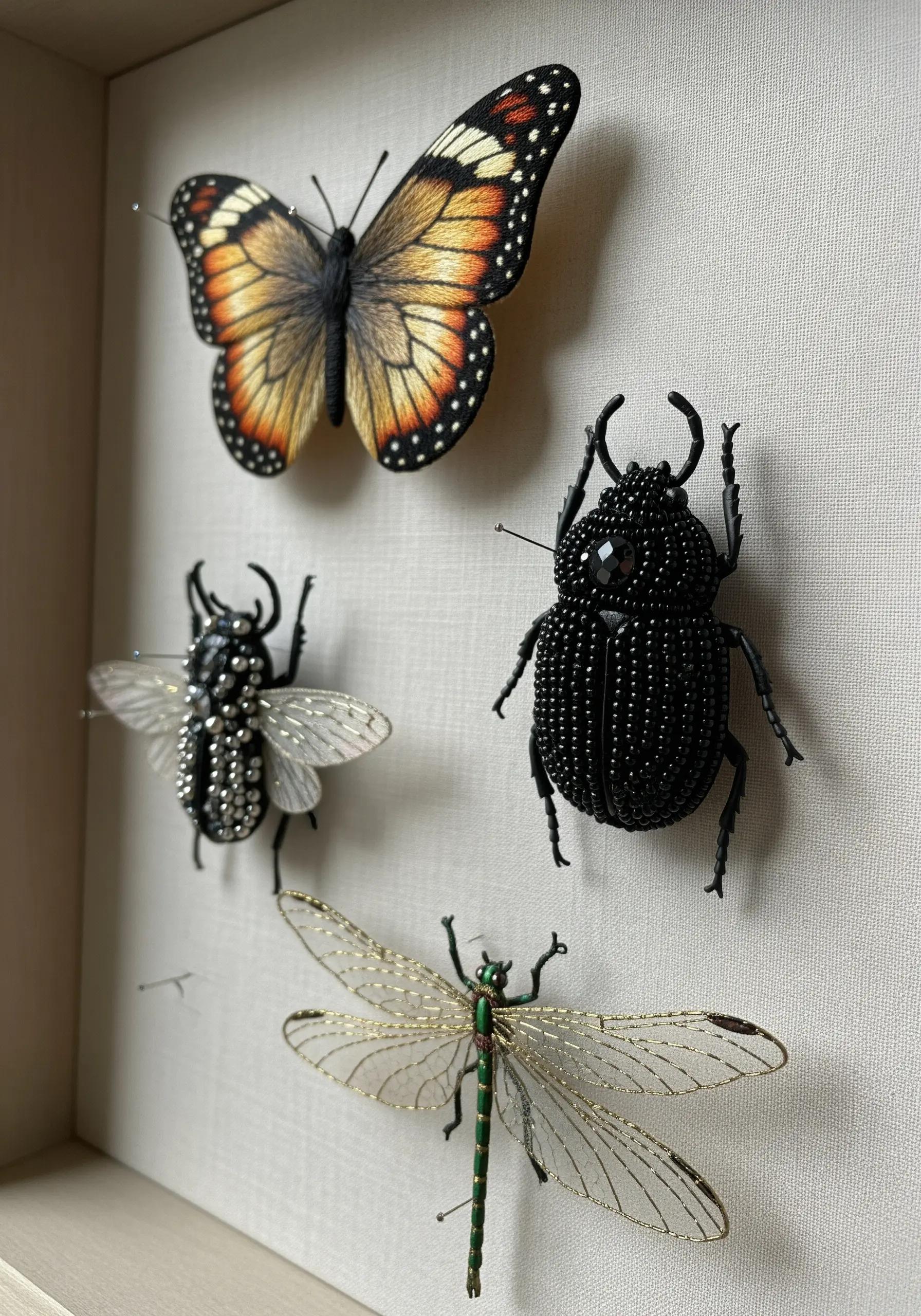 A collection of hyper-realistic 3D embroidered and beaded insects pinned in a shadow box.