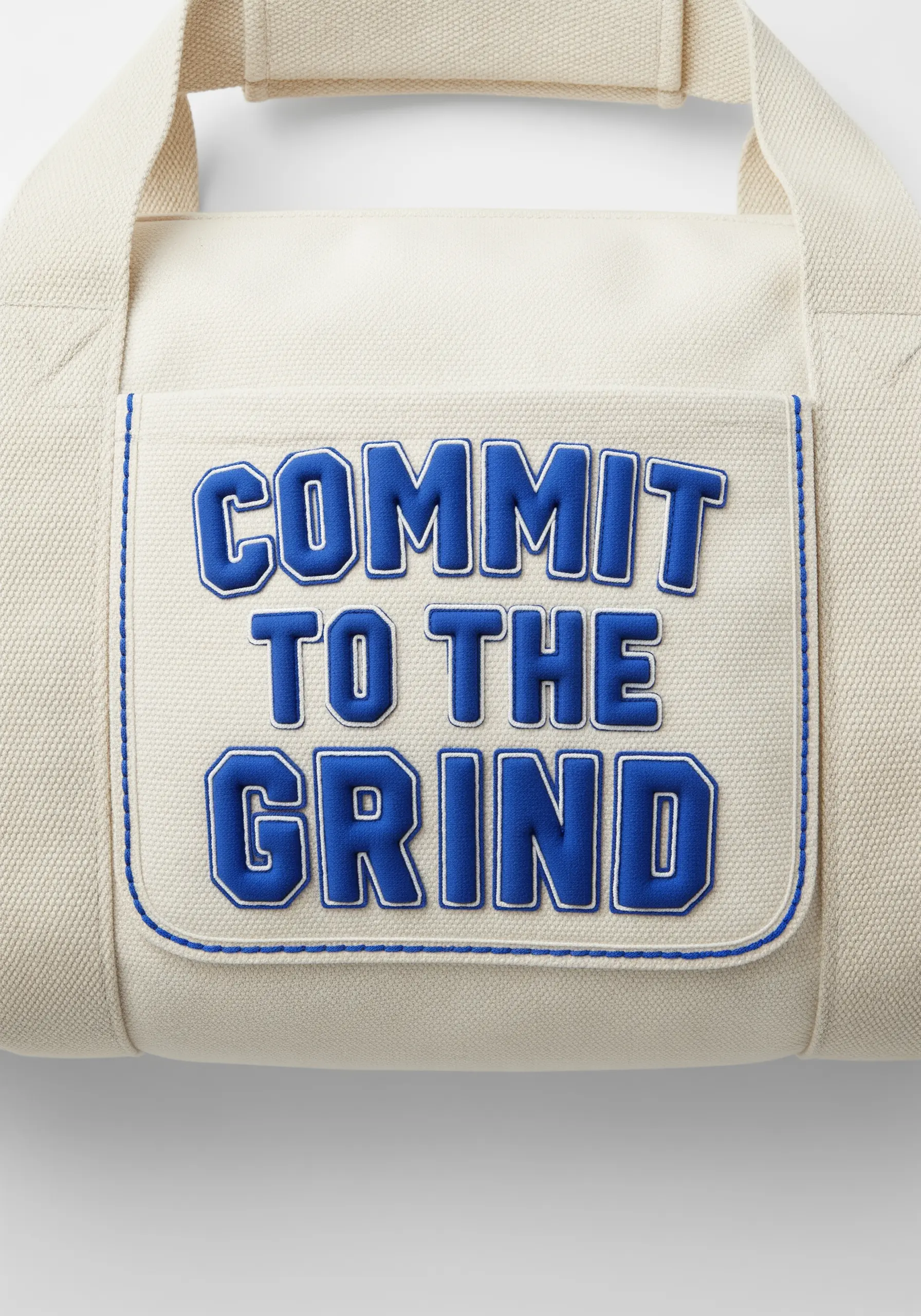 “COMMIT TO THE GRIND” in blue appliqué letters with a satin stitch border on a canvas bag.
