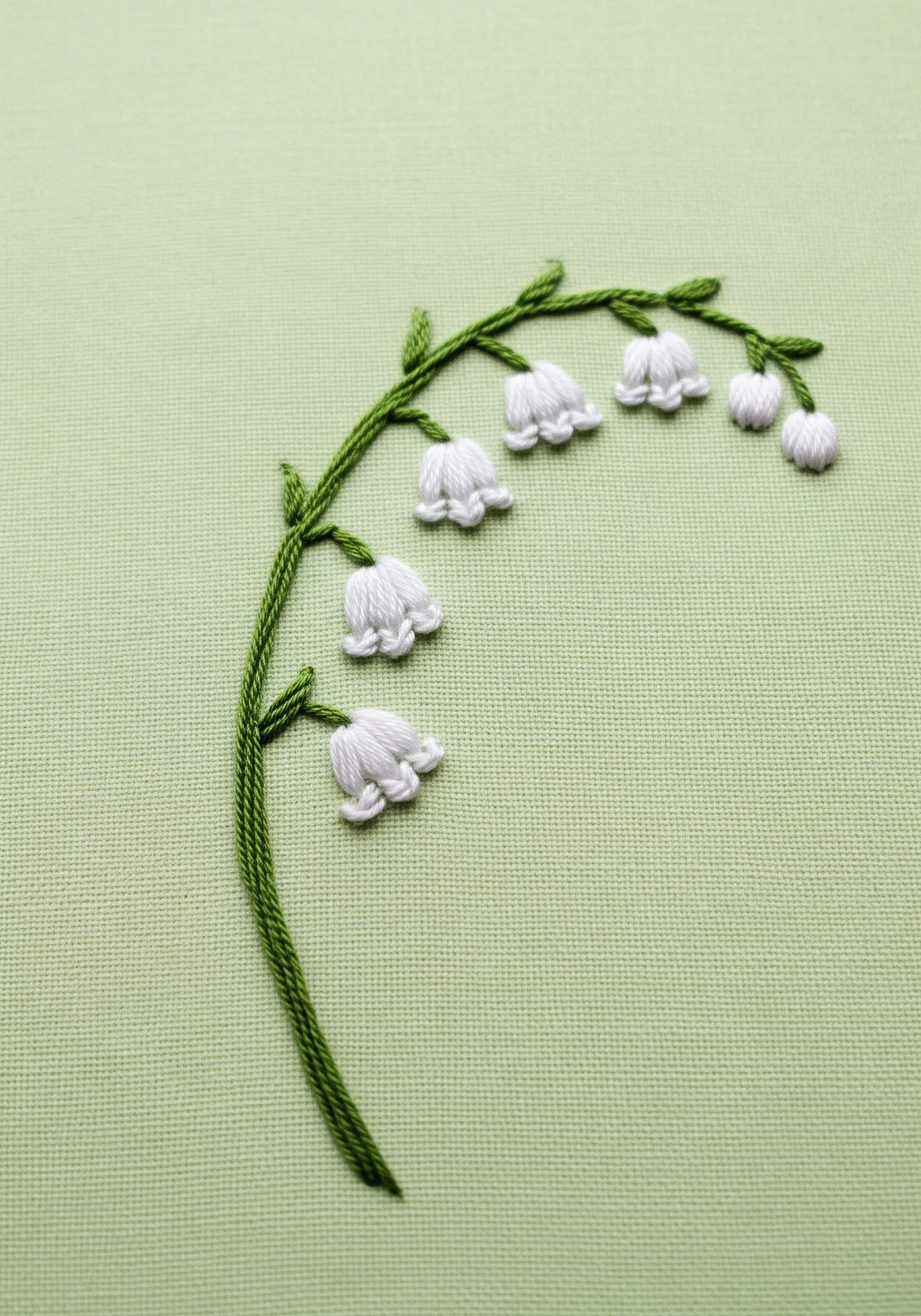 Embroidered Lily of the Valley with dimensional white bell flowers on a green background.