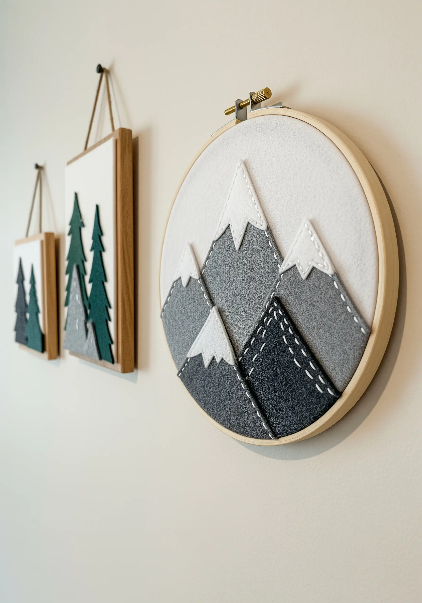 A modern mountain scene created with layered grey felt and decorative white stitches.