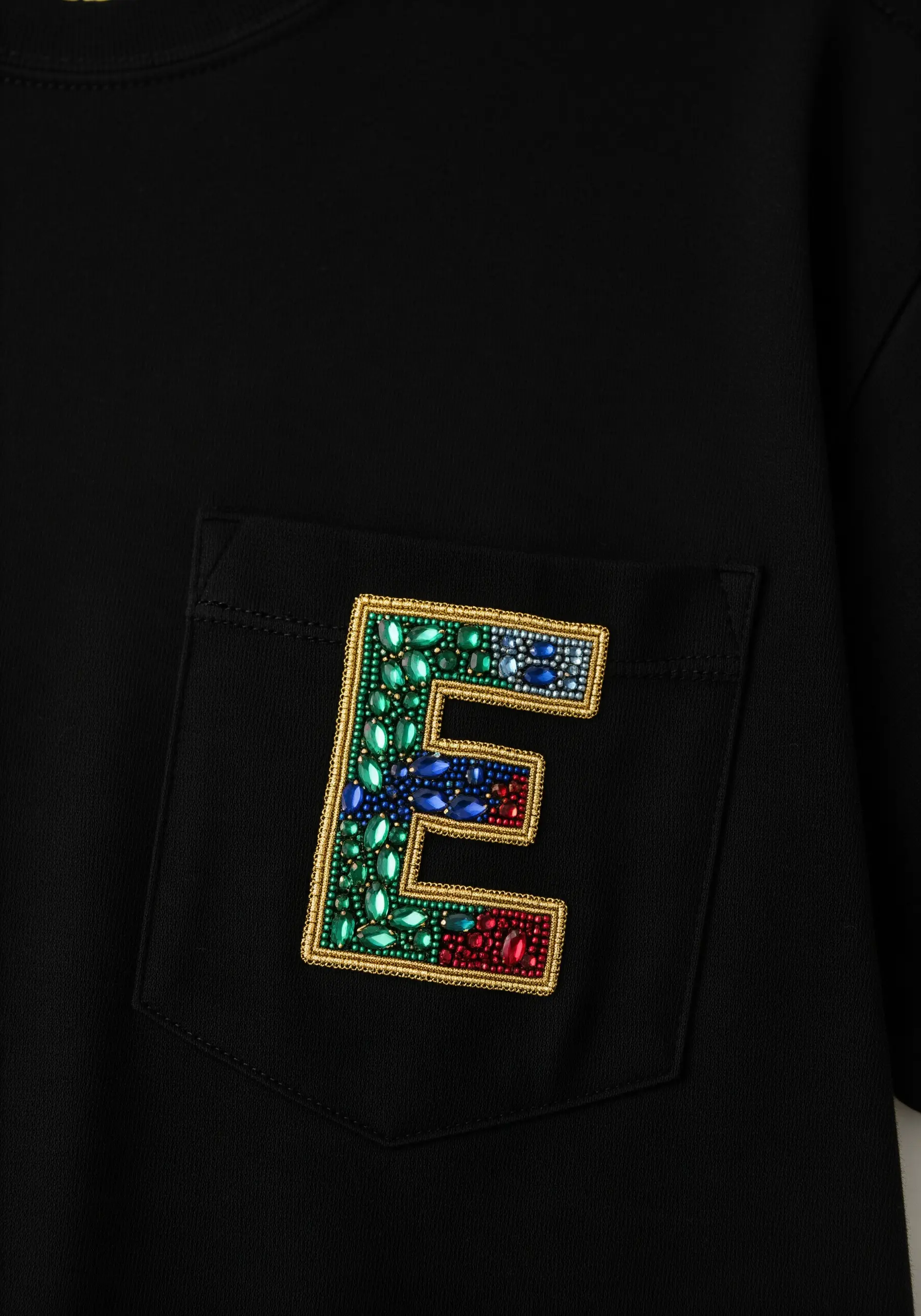 A block letter 'E' on a pocket, filled with sections of red, blue, and green beads.