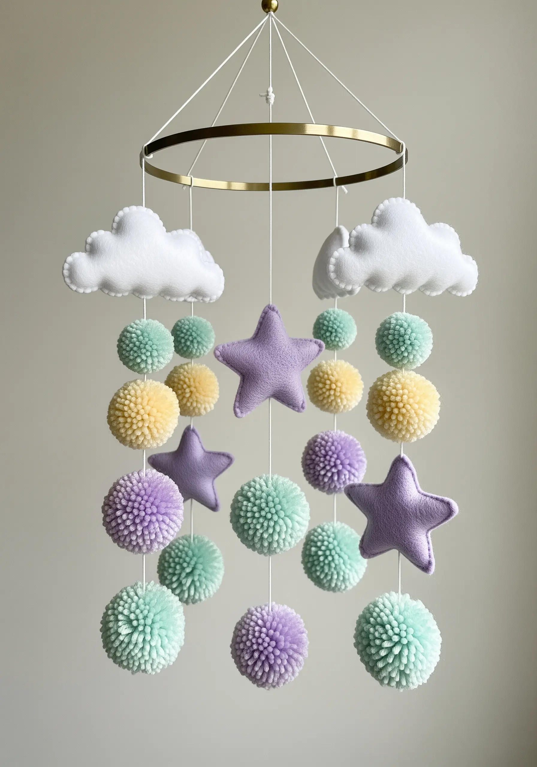Nursery mobile with hand-stitched felt clouds and stars and yarn pom-poms.