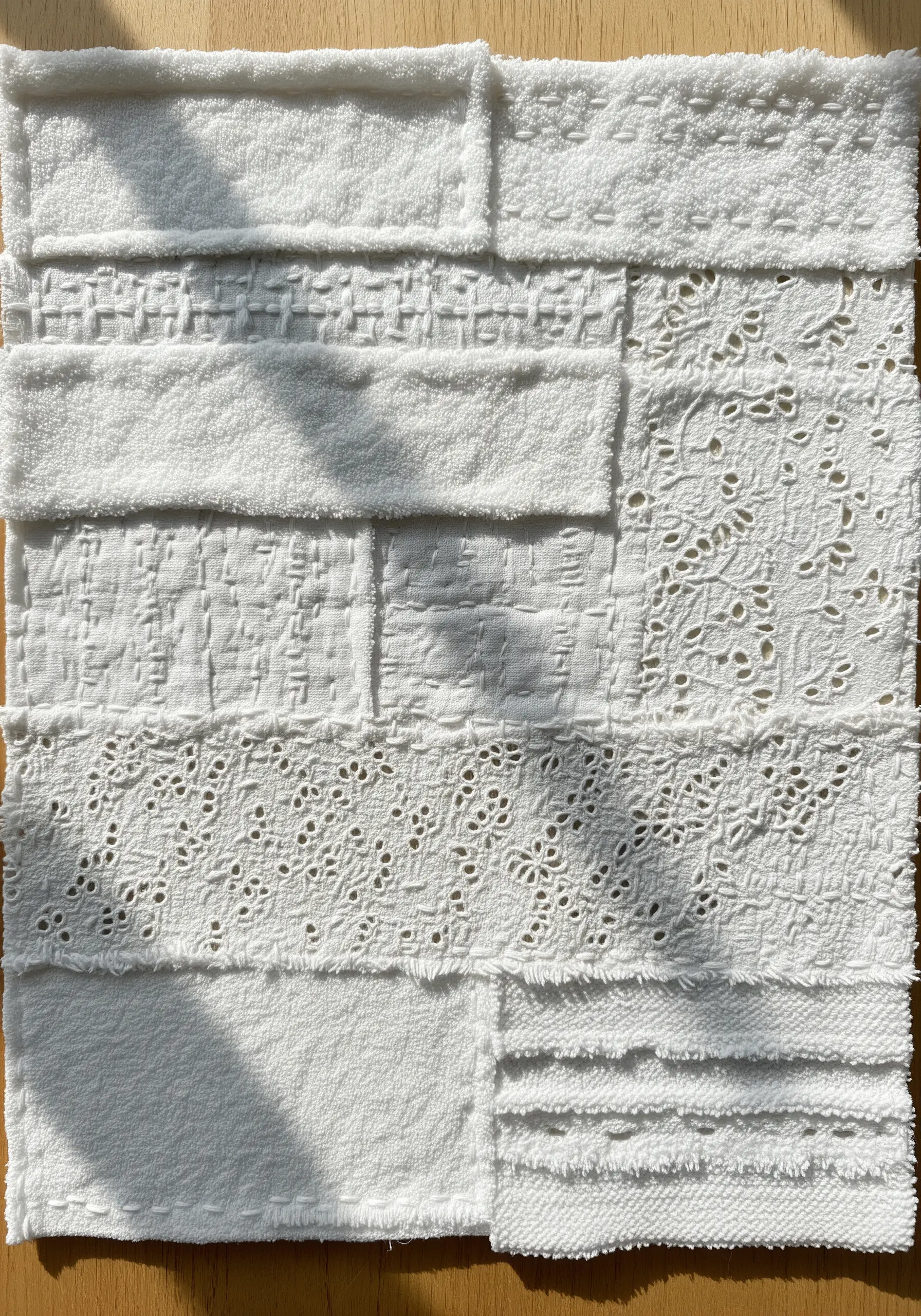 A monochrome white fabric collage featuring a variety of textures, from terry cloth to eyelet lace.