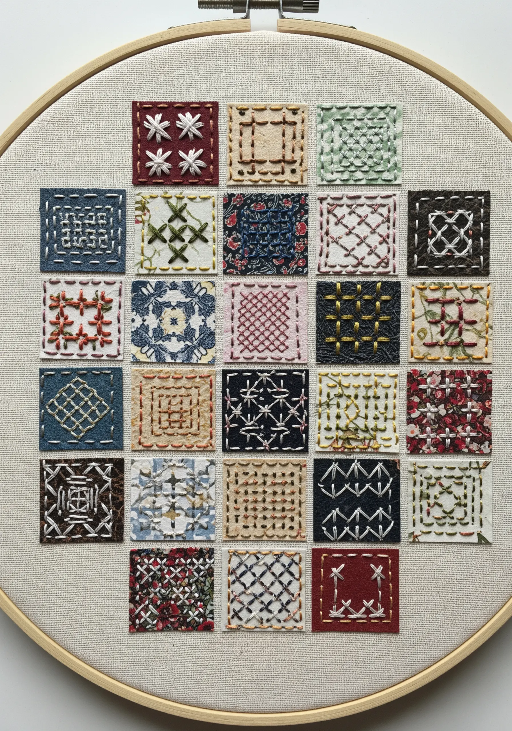 A grid of small paper and fabric squares, each featuring a different embroidery stitch pattern.