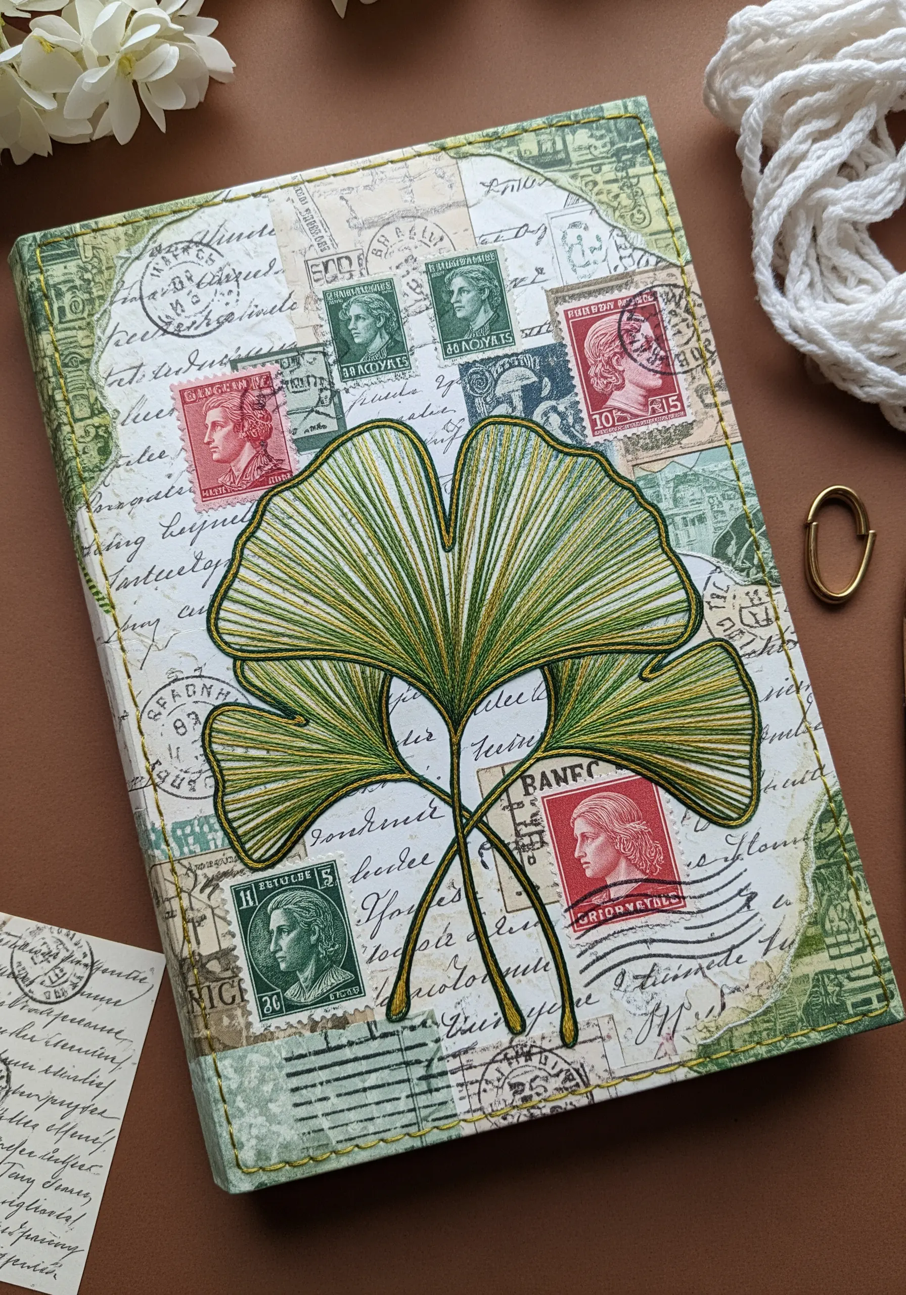 A journal cover with a vintage paper collage and a large, thread-painted ginkgo leaf motif.
