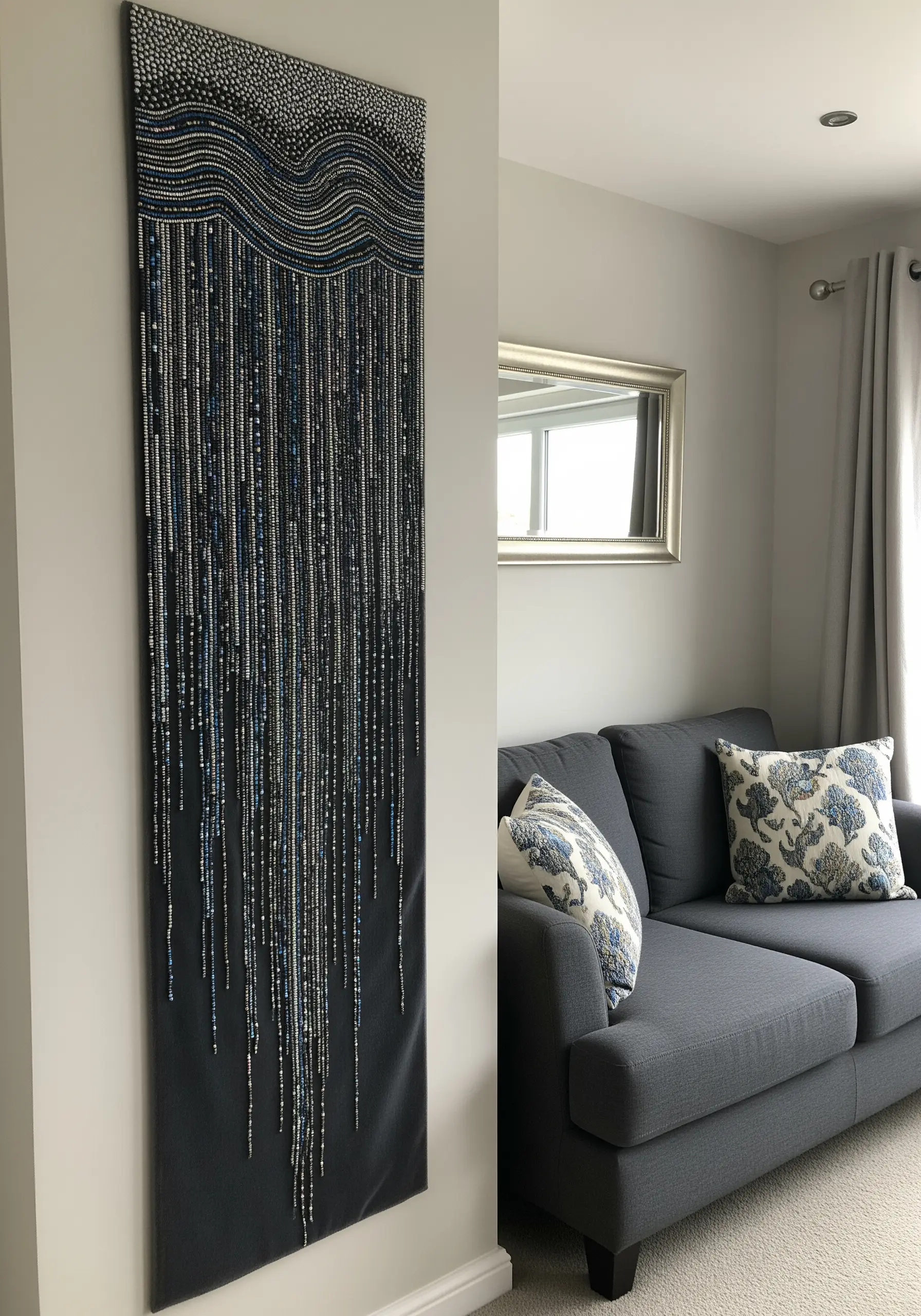 Long beaded wall hanging with vertical strands of blue and silver beads like rain.