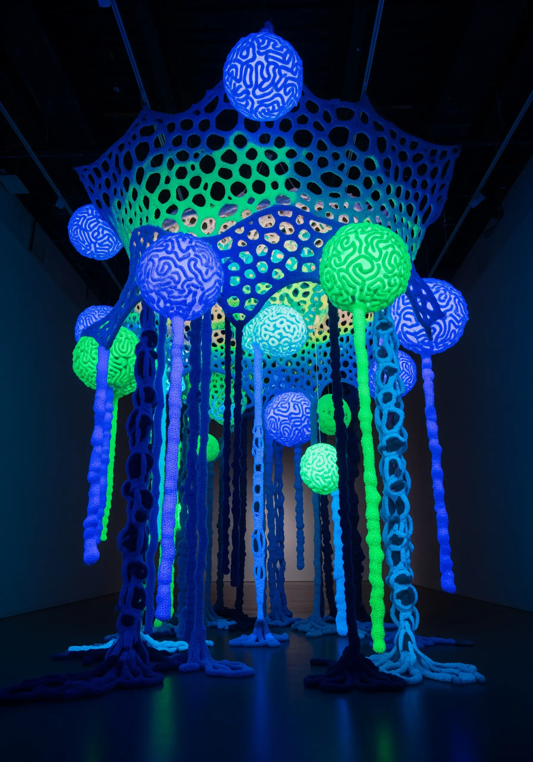 Glowing effect achieved with neon blue and green threads stitched on a black background.