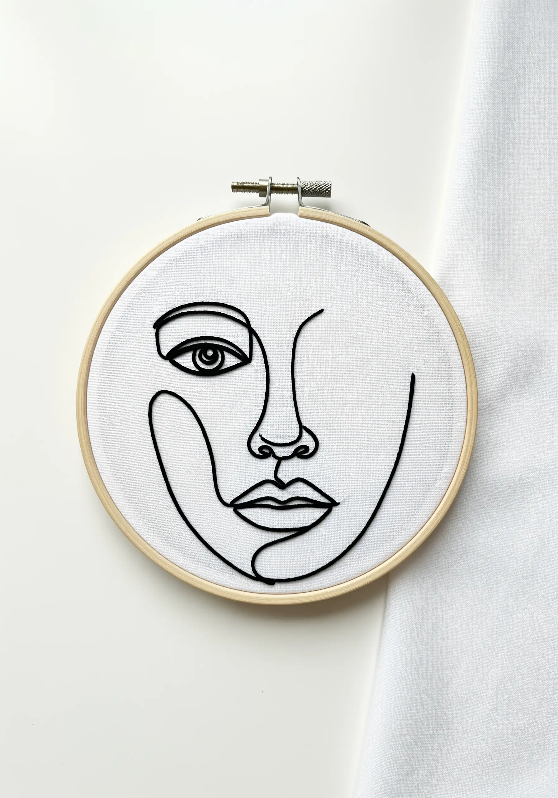 A minimalist line art portrait of a face stitched in bold black thread.