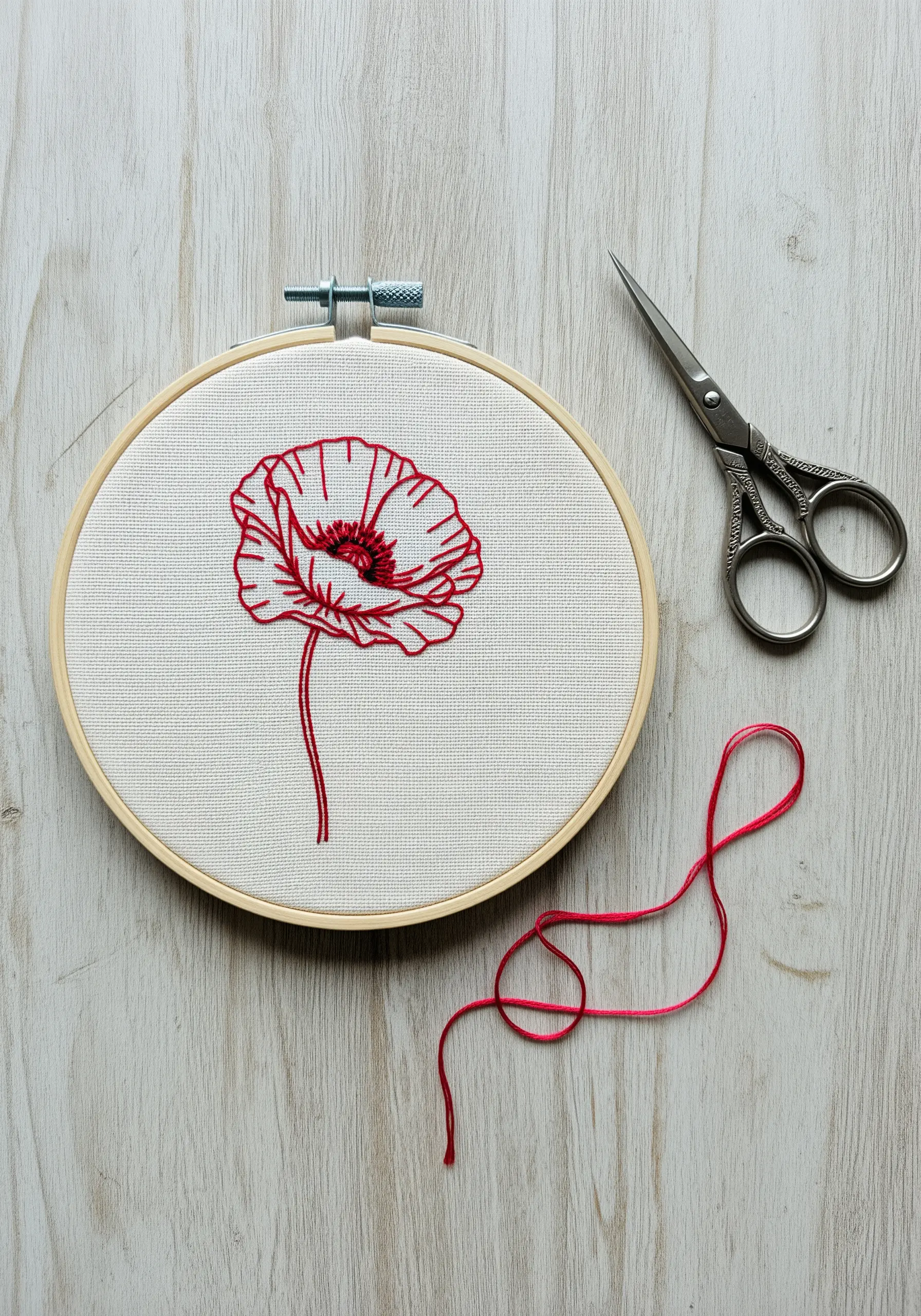 Red line art embroidery of a poppy flower in a hoop.