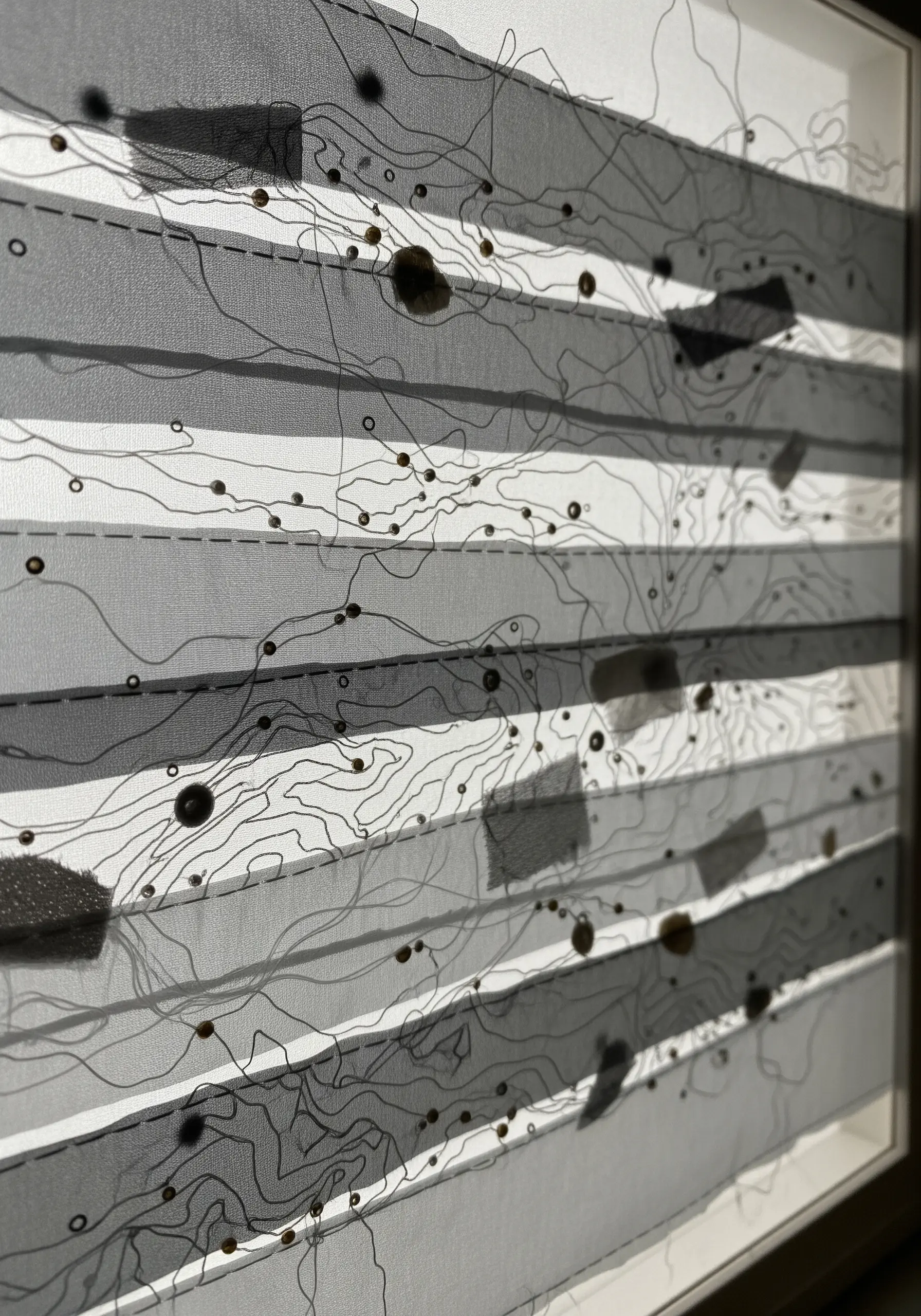 Abstract embroidery on layered, semi-transparent fabric creating depth and shadow effects.
