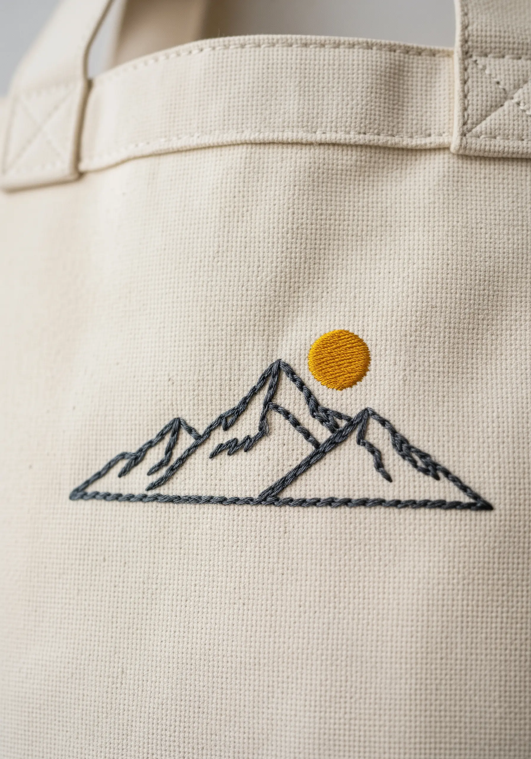A minimal embroidery of a mountain range outline with a solid yellow sun.