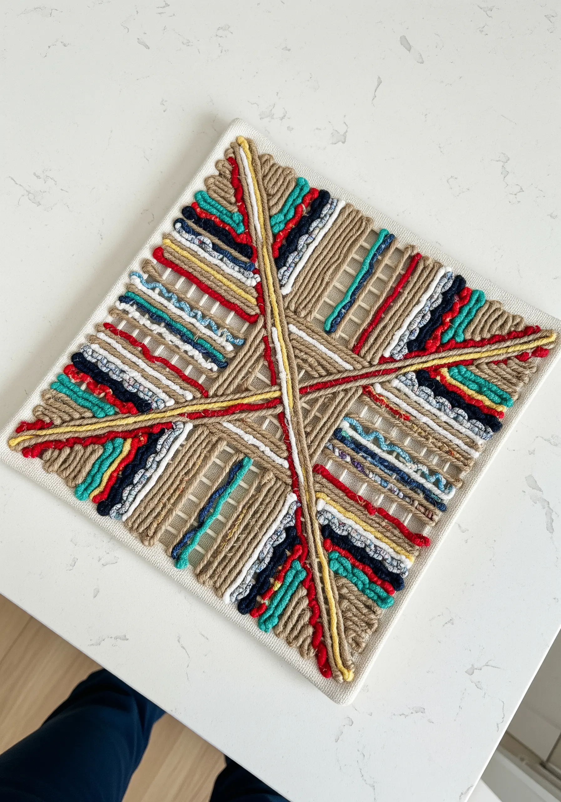 Geometric string art on a square canvas featuring intersecting lines of colorful wrapped yarn.