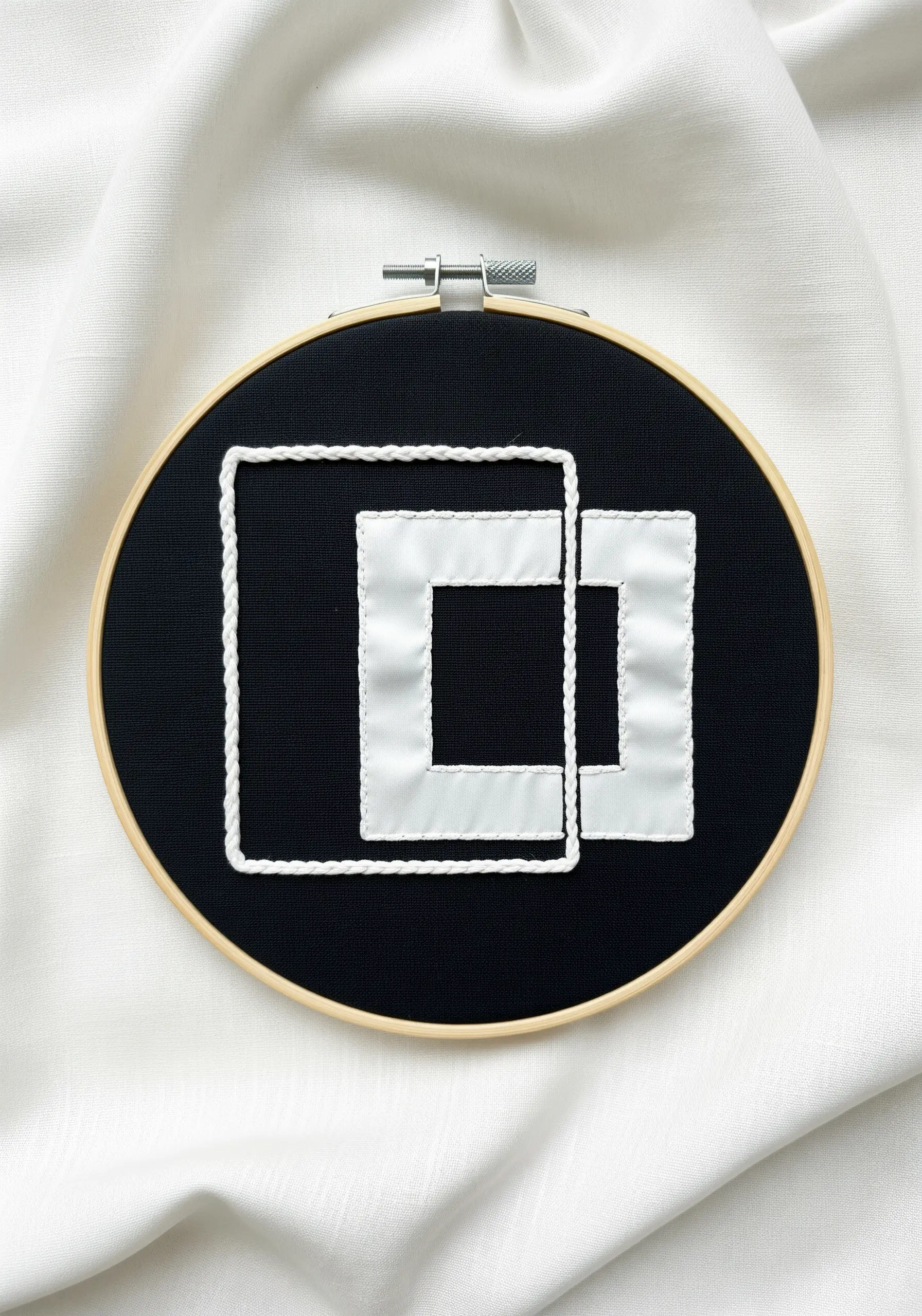 Two overlapping white squares on a black background, one appliquéd and one outlined.