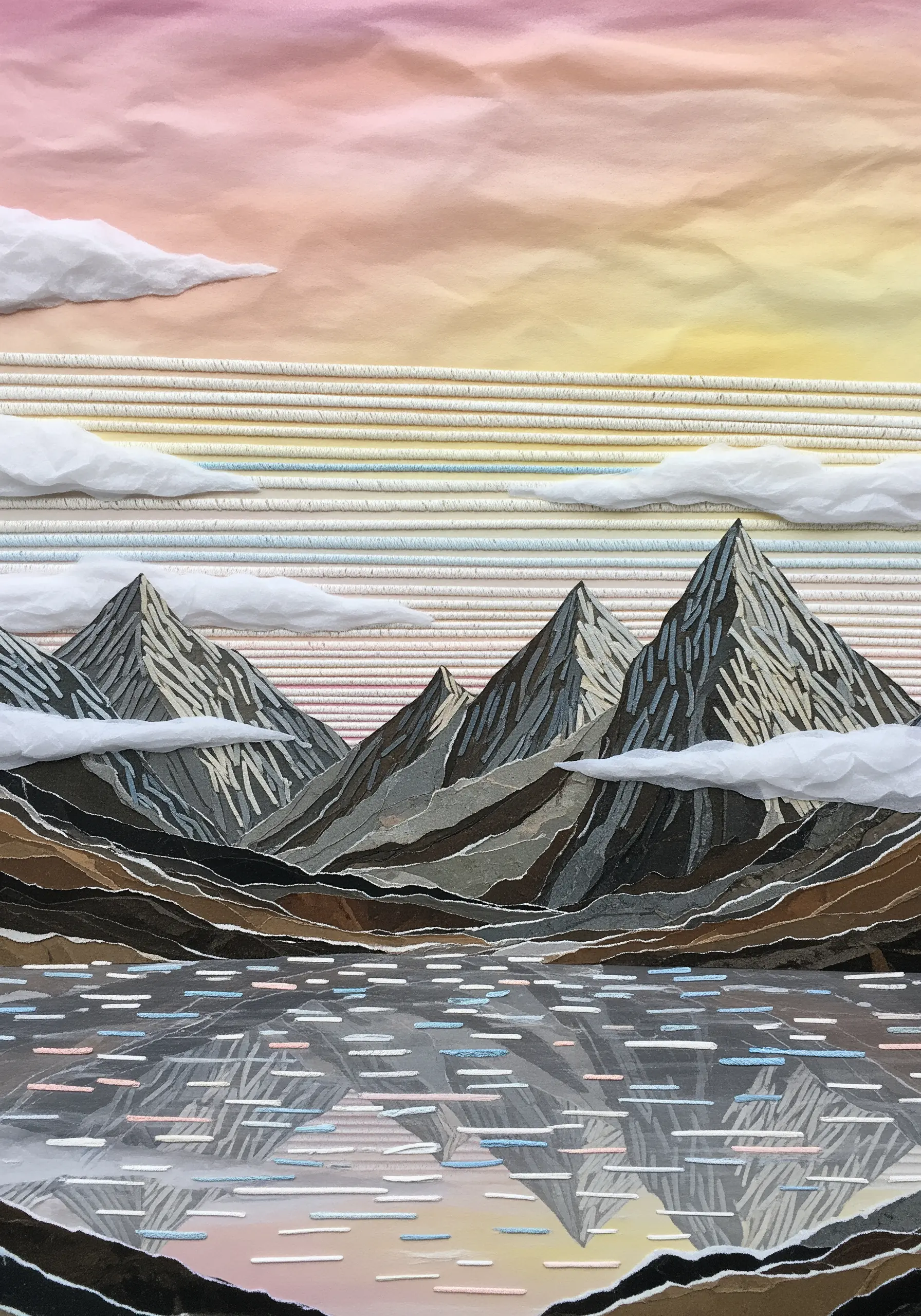 A layered paper collage of a mountain range reflecting in a lake at sunset.