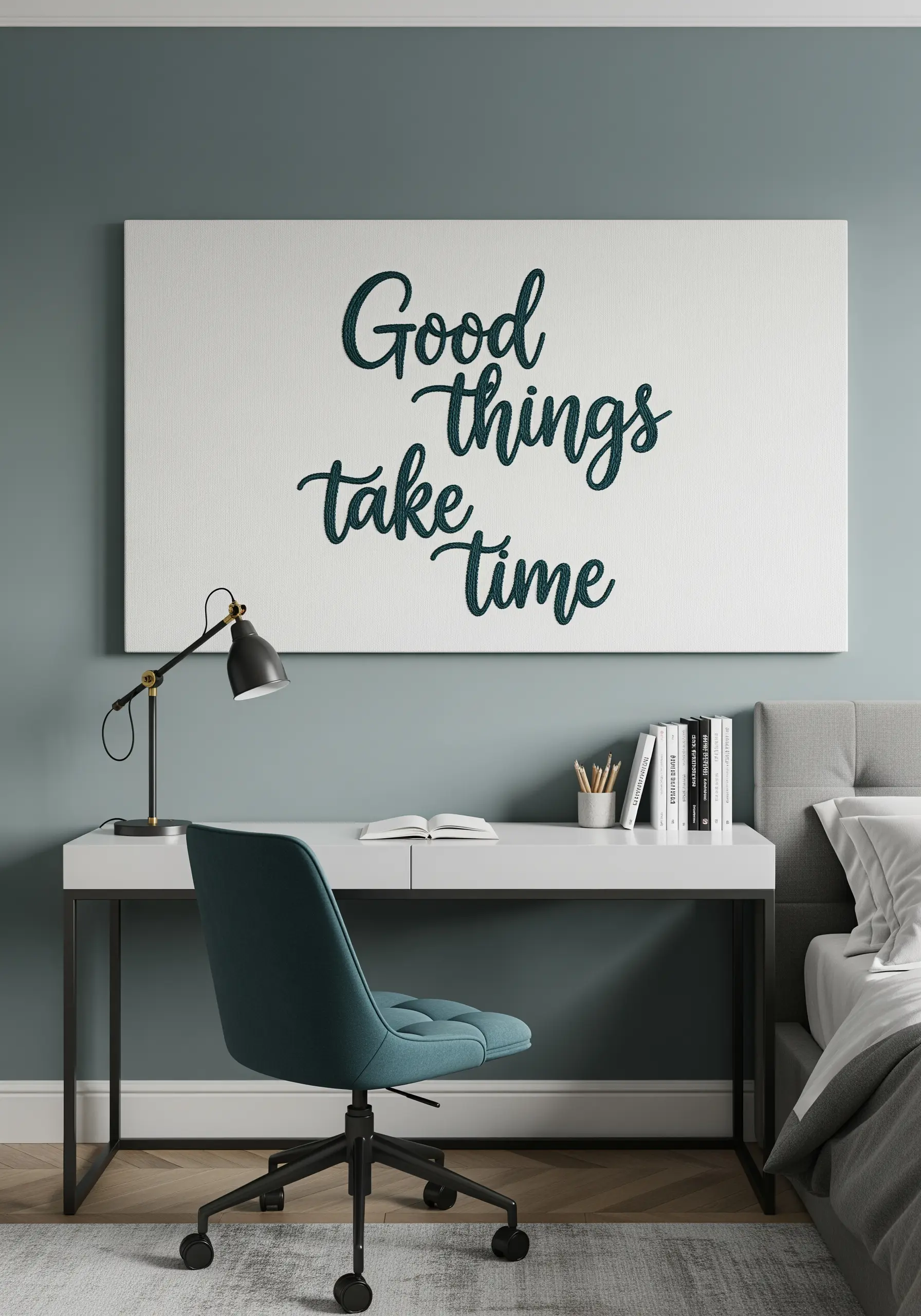 A large canvas above a desk featuring the embroidered quote 'Good things take time.'