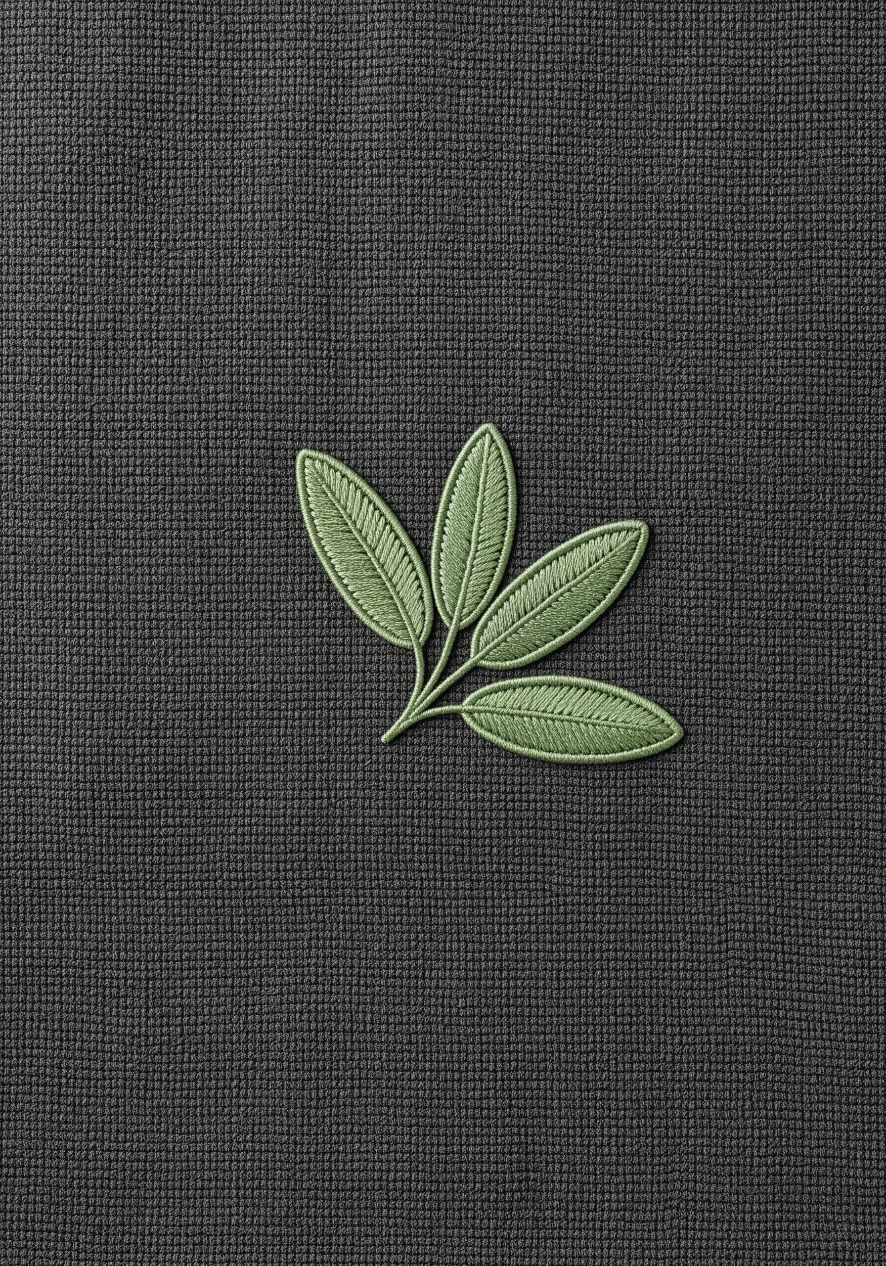 A sprig of sage leaves embroidered in two shades of green on a dark gray towel.
