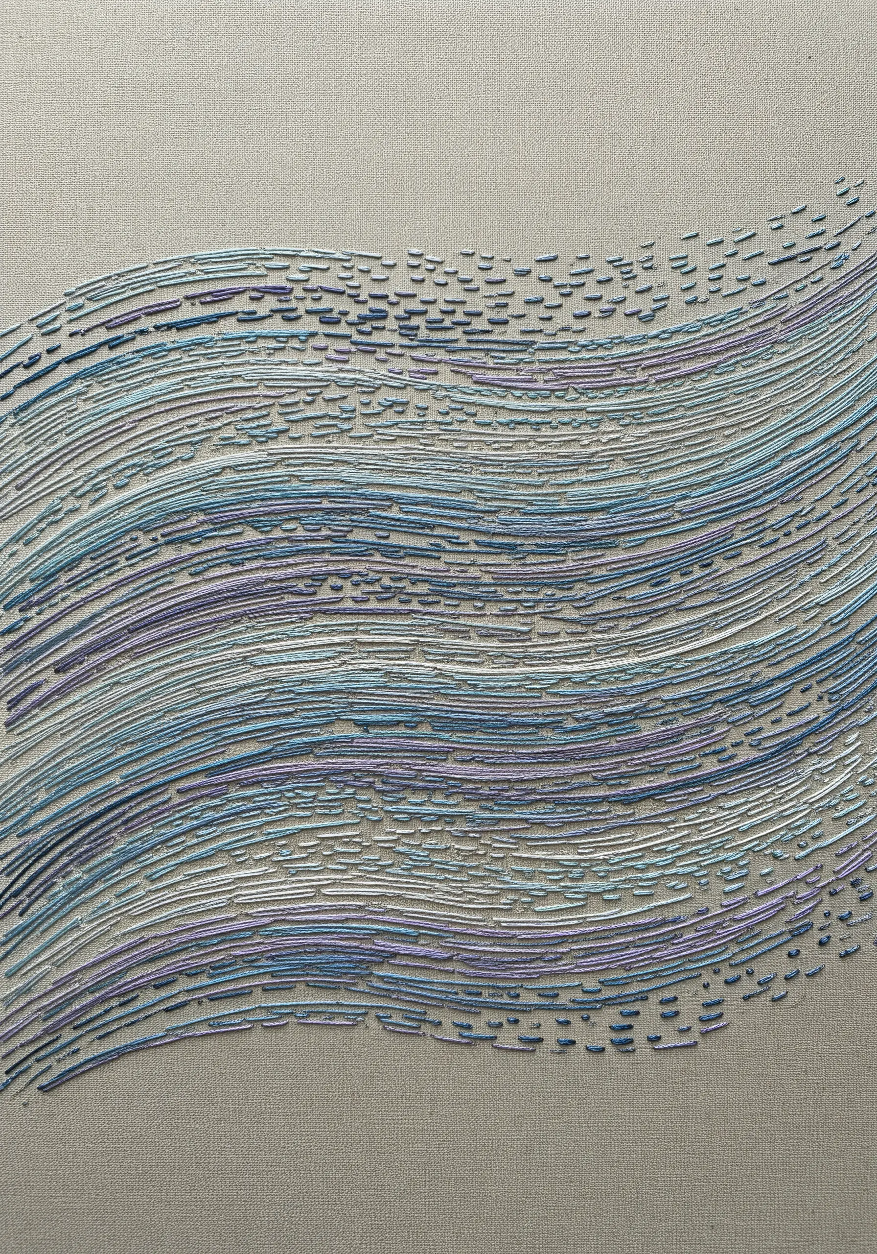 Abstract embroidery of flowing waves made from scattered seed stitches in blue and purple.