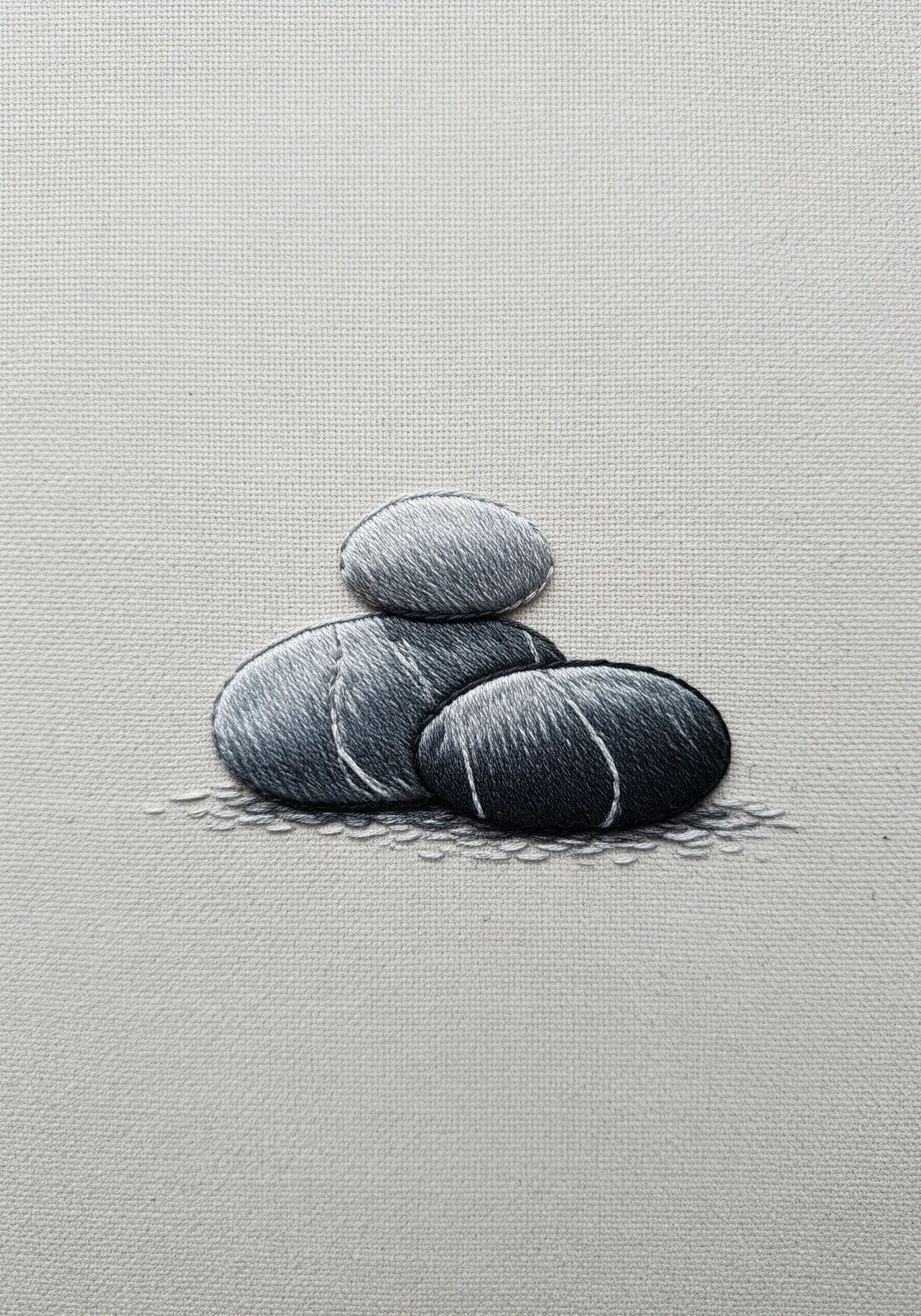 Three realistically embroidered pebbles using thread painting to show smooth gradients.