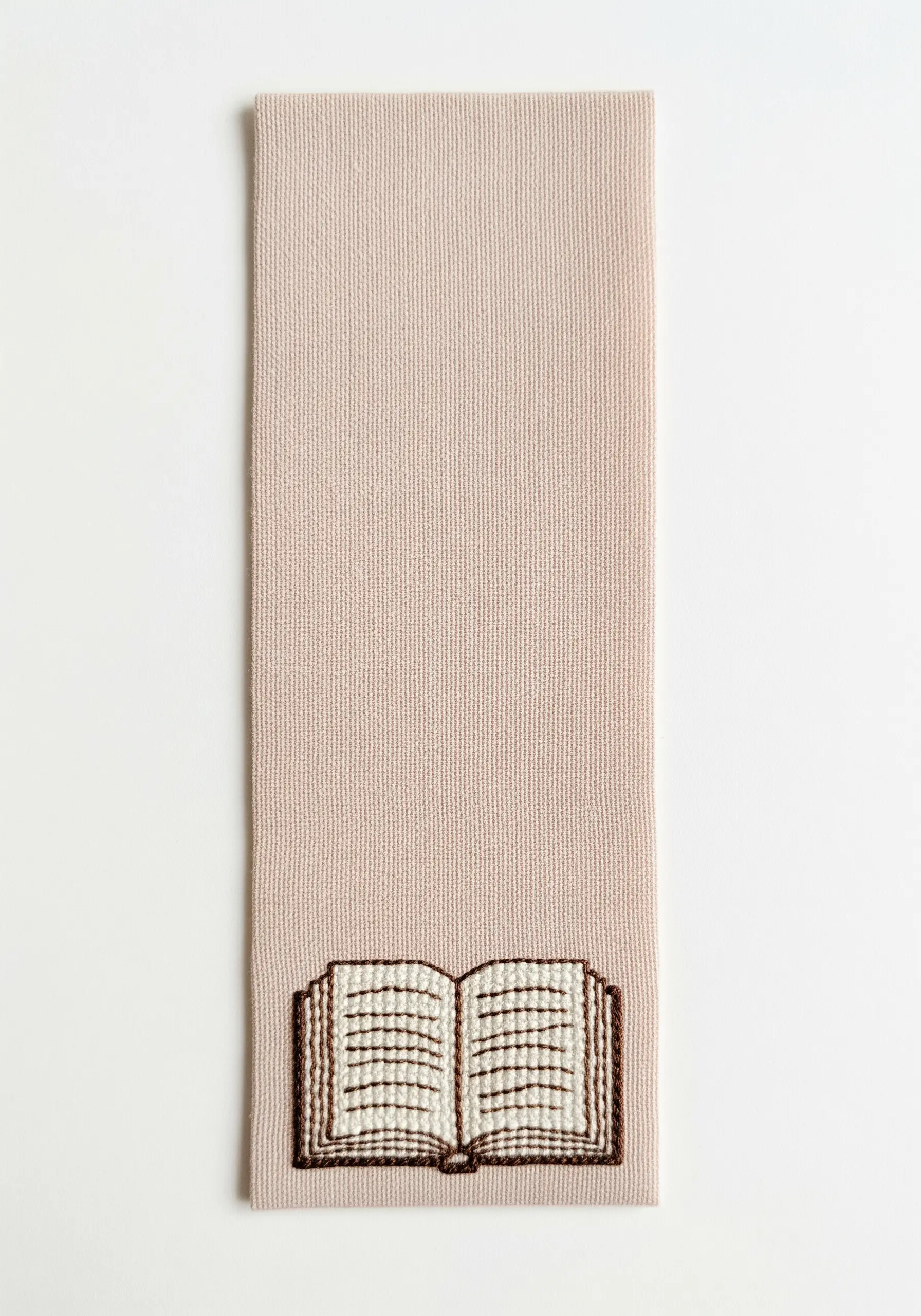 An embroidered open book with woven stitches to represent text on a pink bookmark.