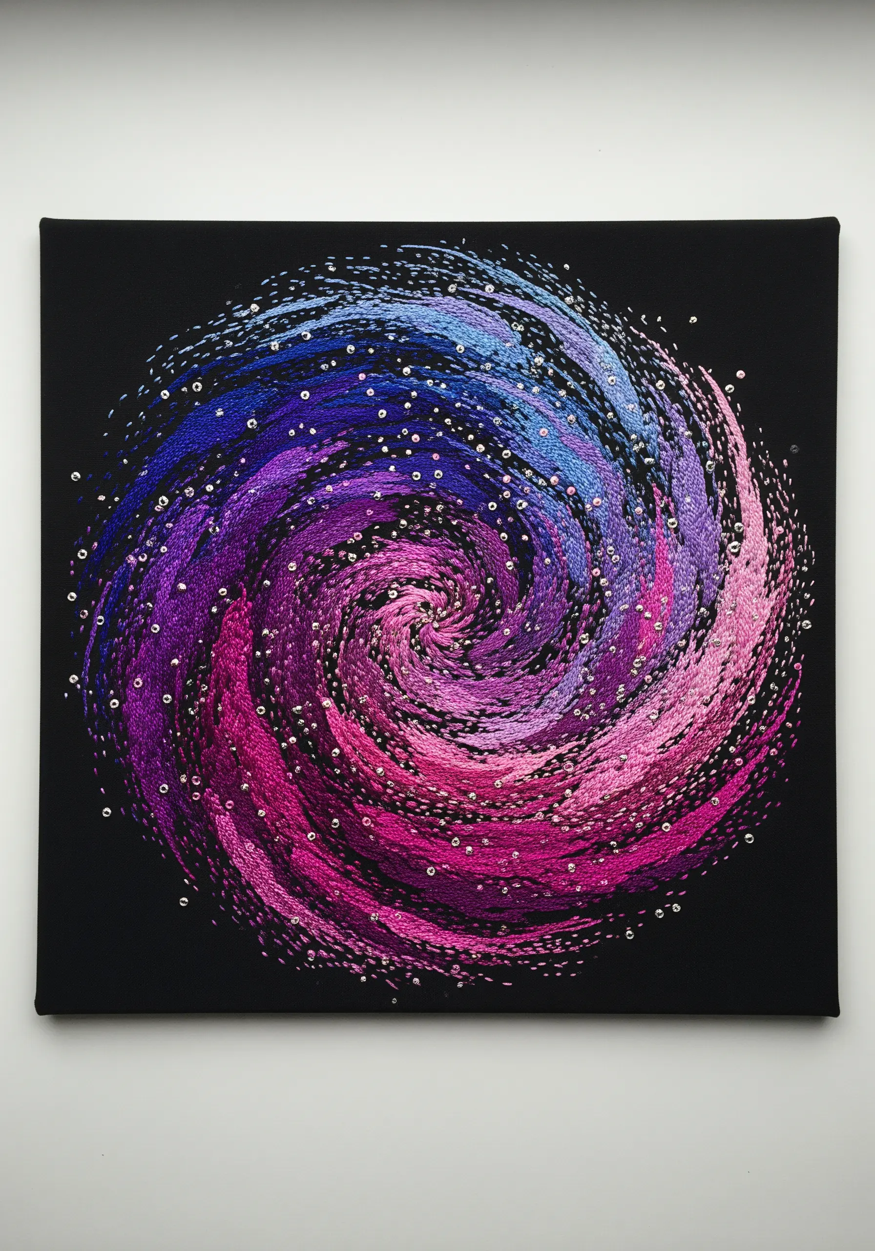 A swirling galaxy embroidery in blue, purple, and pink with scattered silver beads.