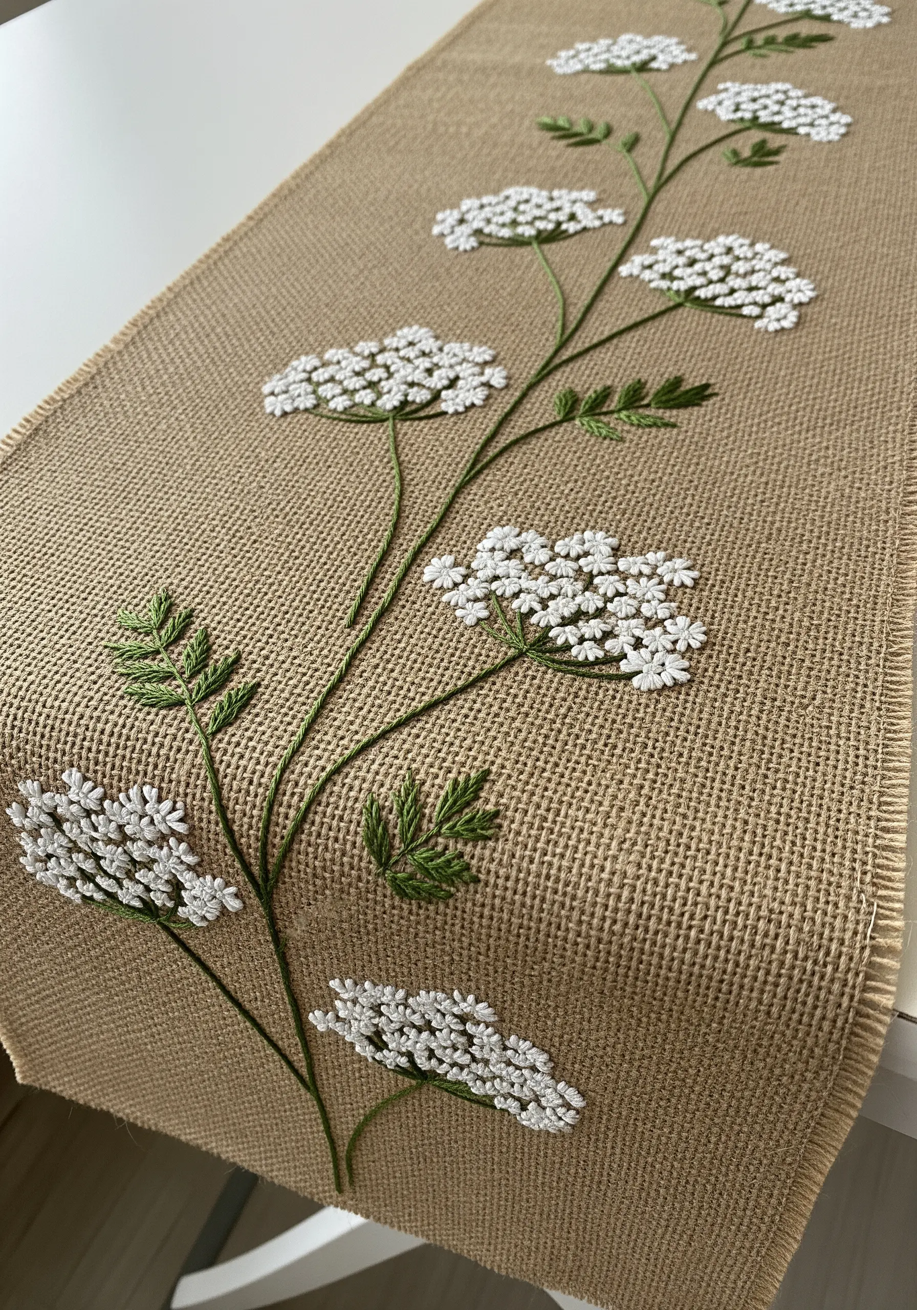 Queen Anne's Lace embroidered with white French knots on a burlap table runner.