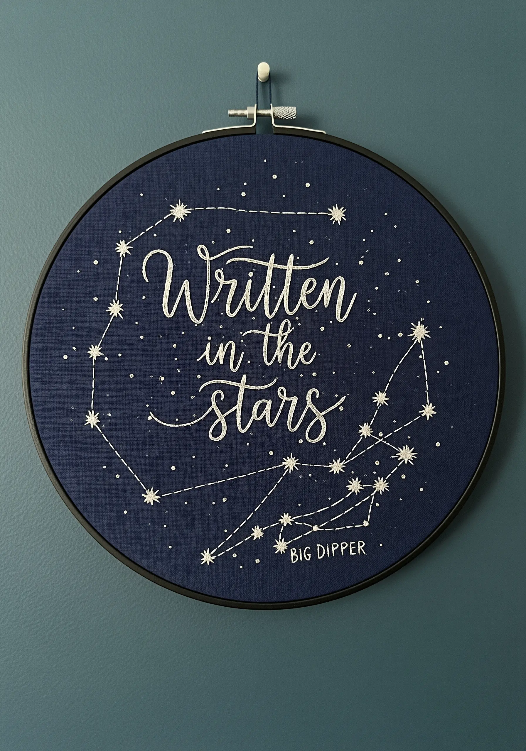 “Written in the stars” quote embroidered with constellations on dark blue fabric.