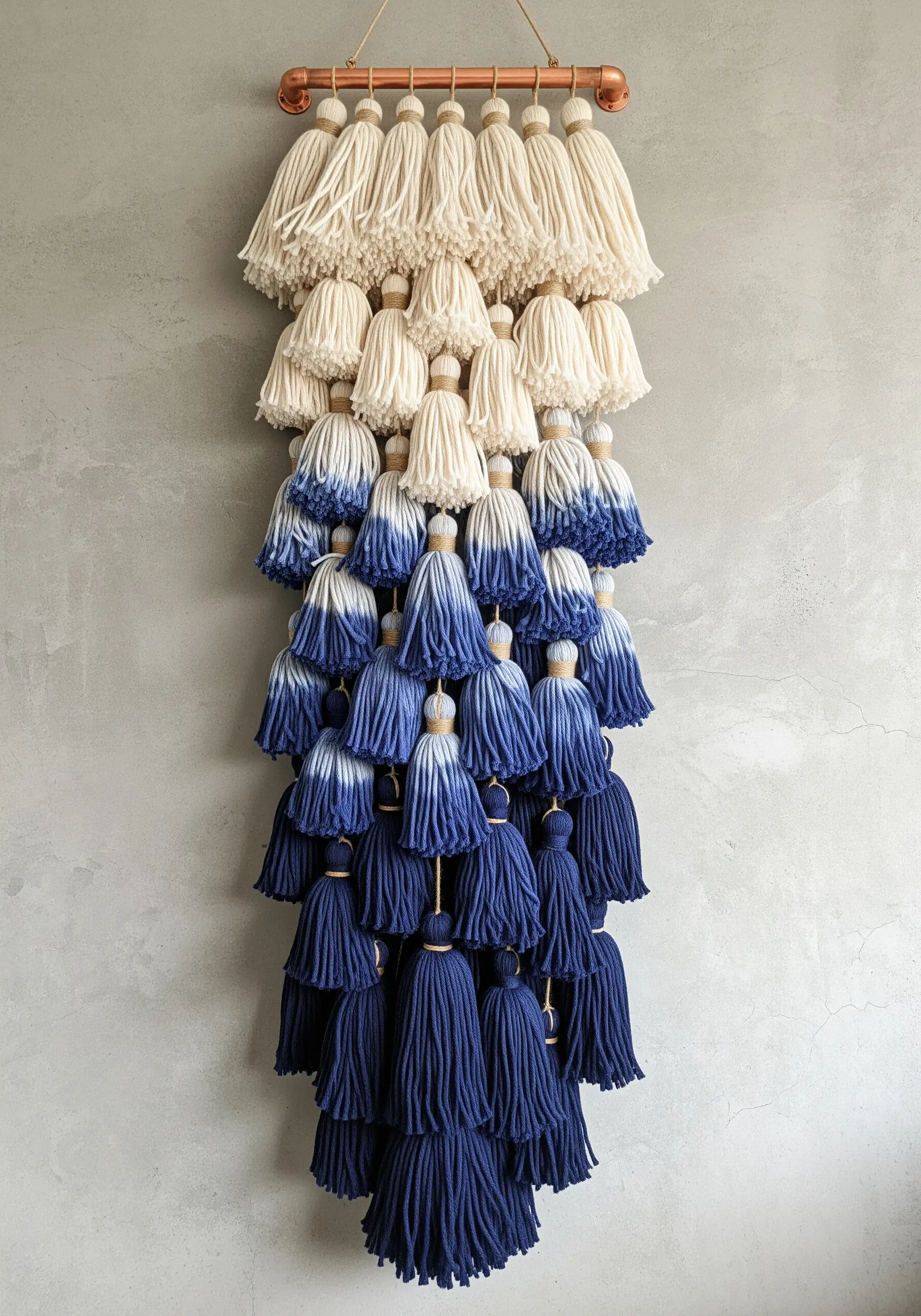 A wall hanging made of many tassels dip-dyed in shades of indigo, creating a gradient effect.