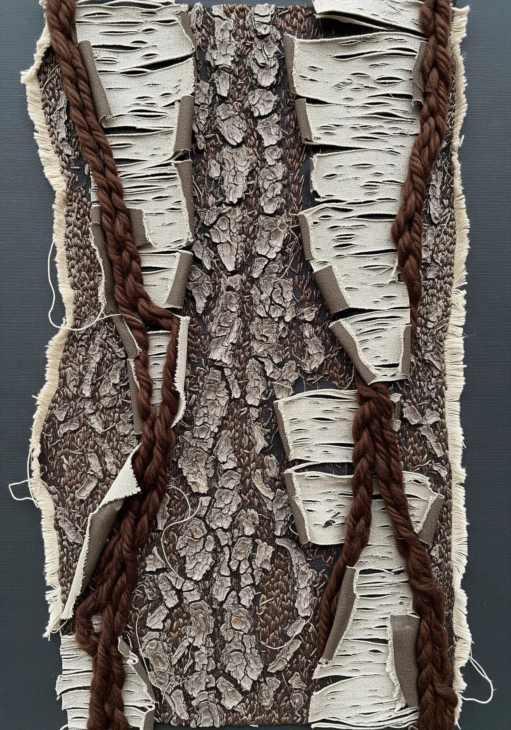 Mixed-media textile art with slashed and frayed fabric revealing a bark pattern underneath.