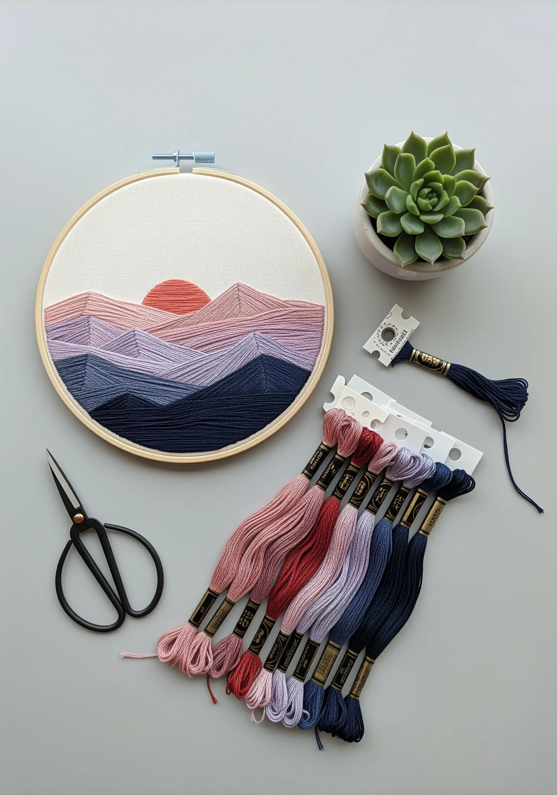 An embroidered mountain landscape with clean, color-blocked satin stitch in shades of purple and pink.