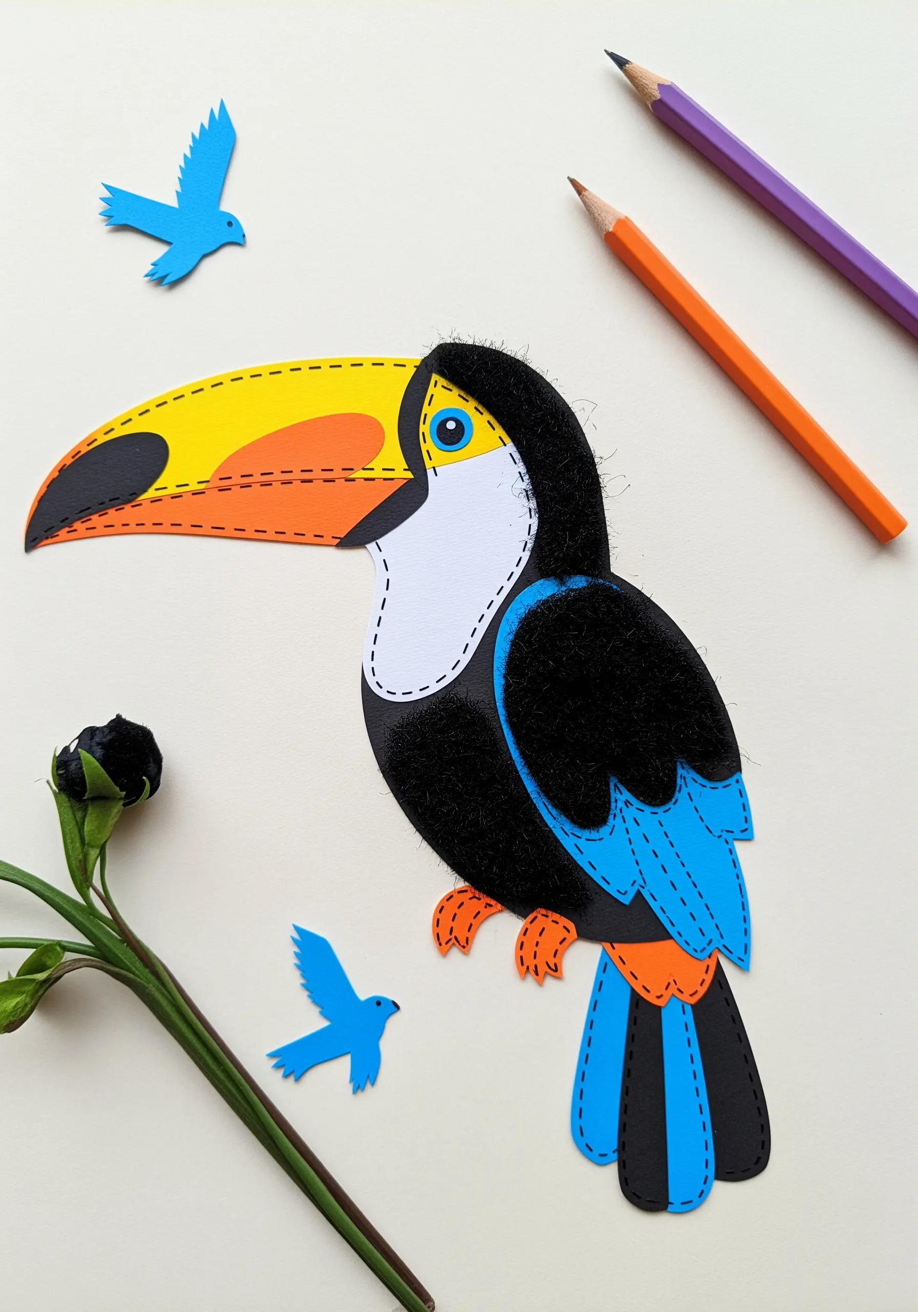 A colorful toucan collage made from paper and felt, outlined with a simple running stitch.