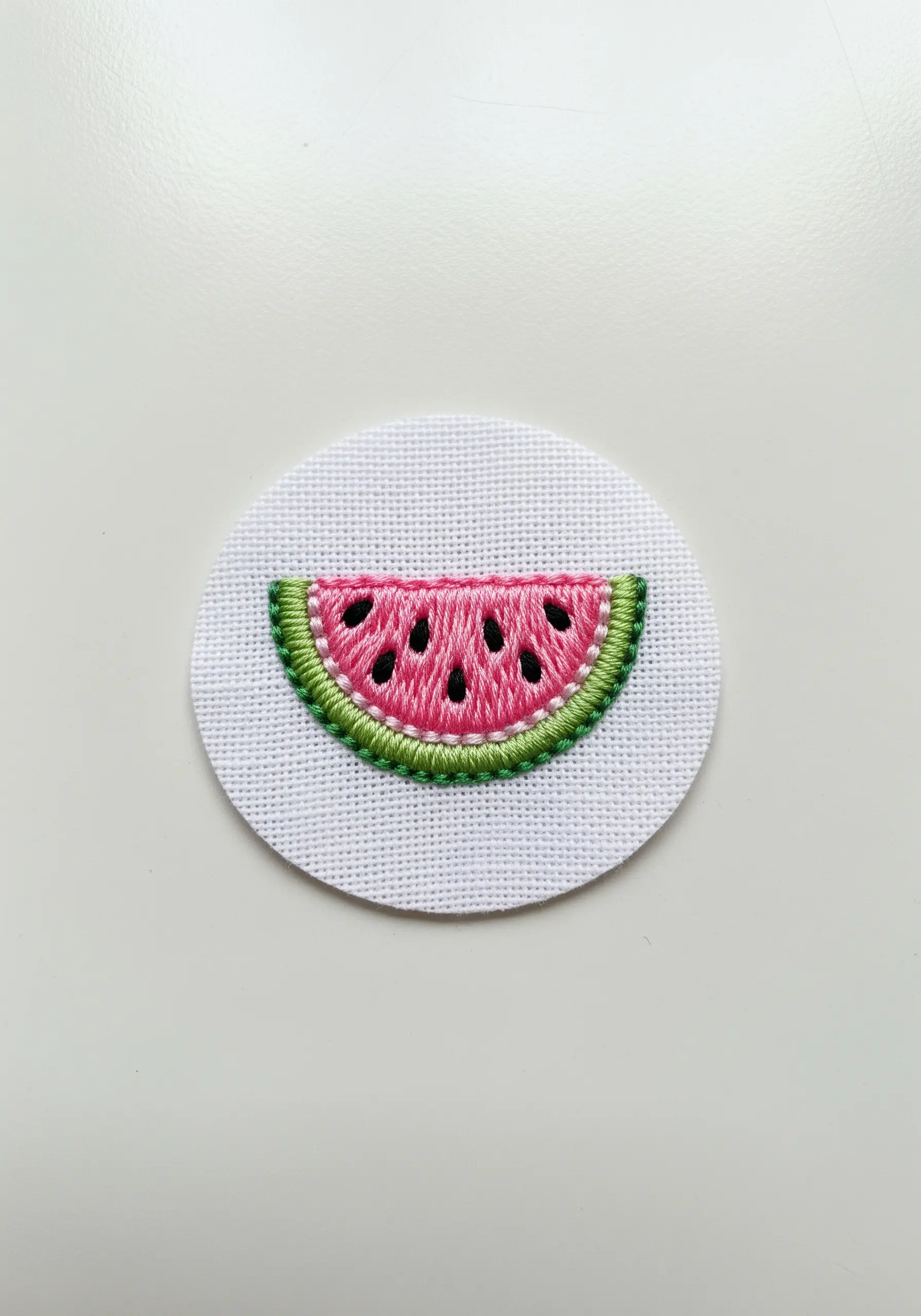 A small embroidered watermelon slice patch with clean outlines and French knot seeds.