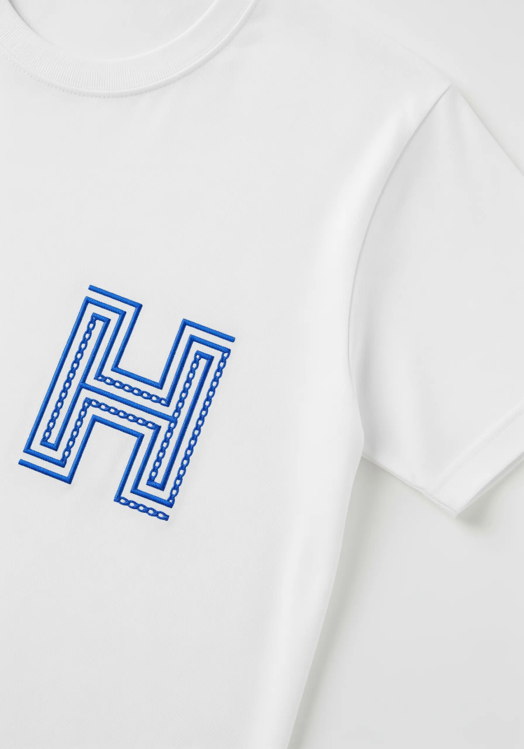A graphic letter 'H' embroidered in blue with repeating line and chain stitch patterns.