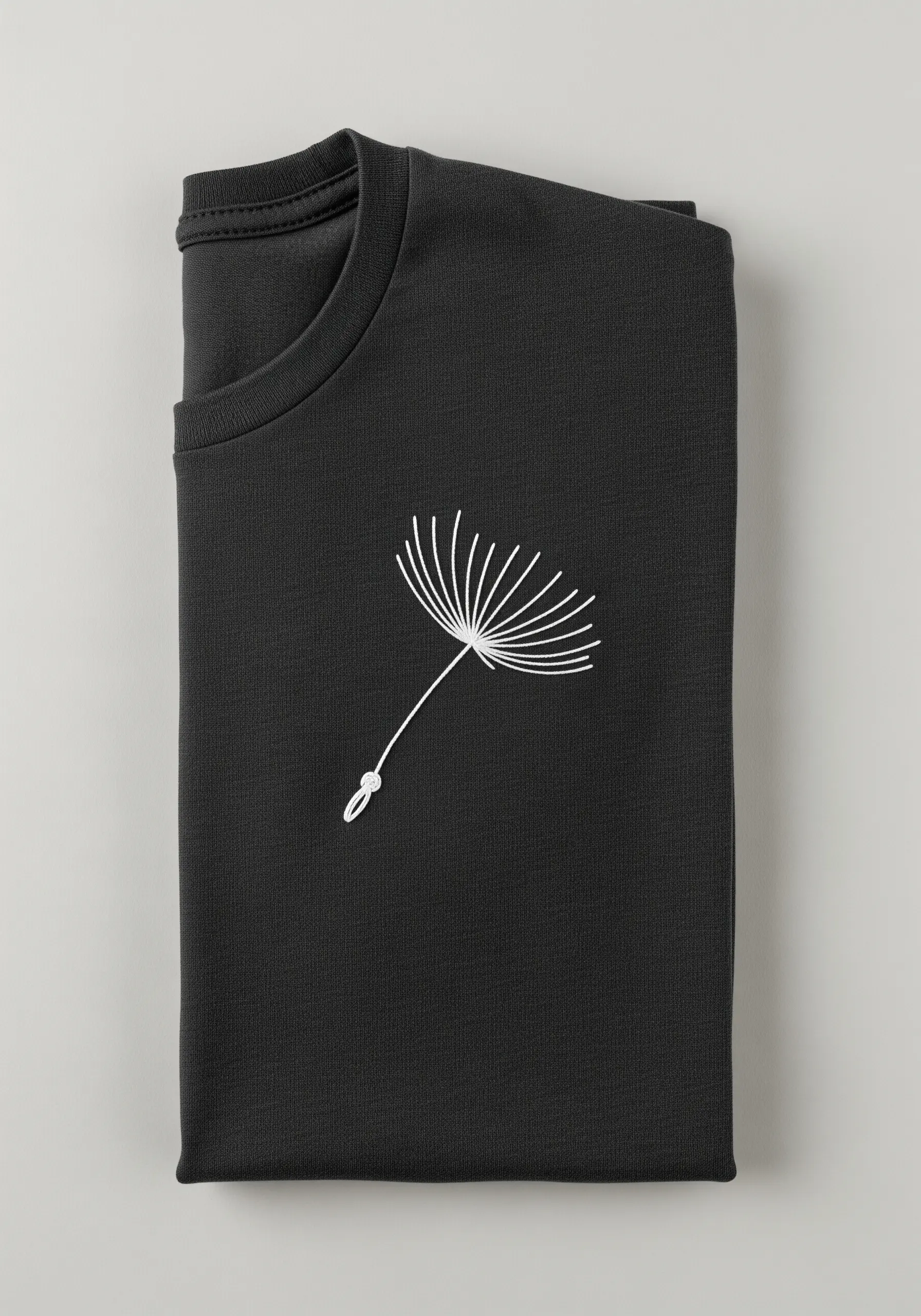 A delicate white line art dandelion seed head embroidered on a black sweatshirt.
