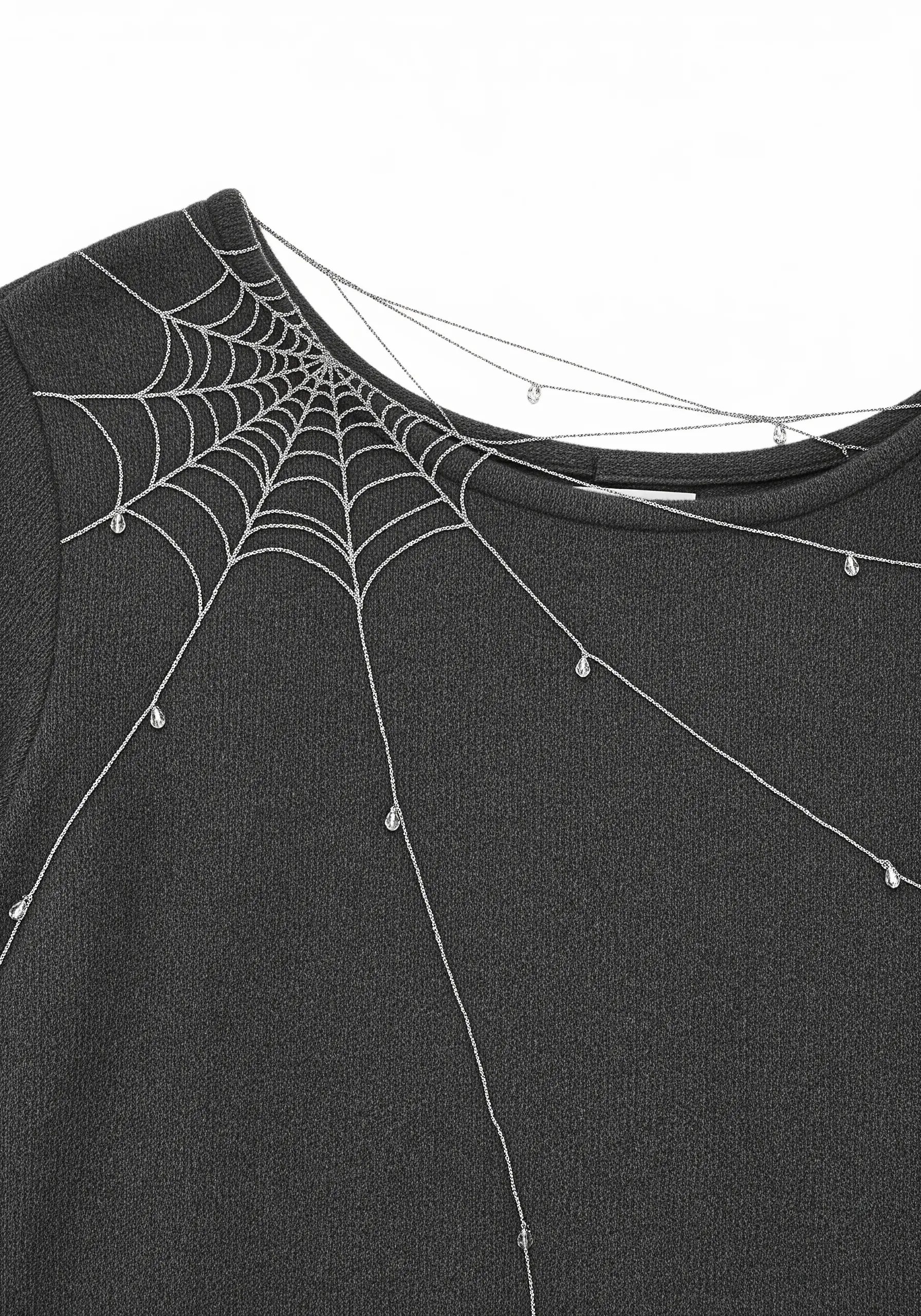 A delicate spiderweb in silver thread with crystal dewdrops across the neckline of a black top.