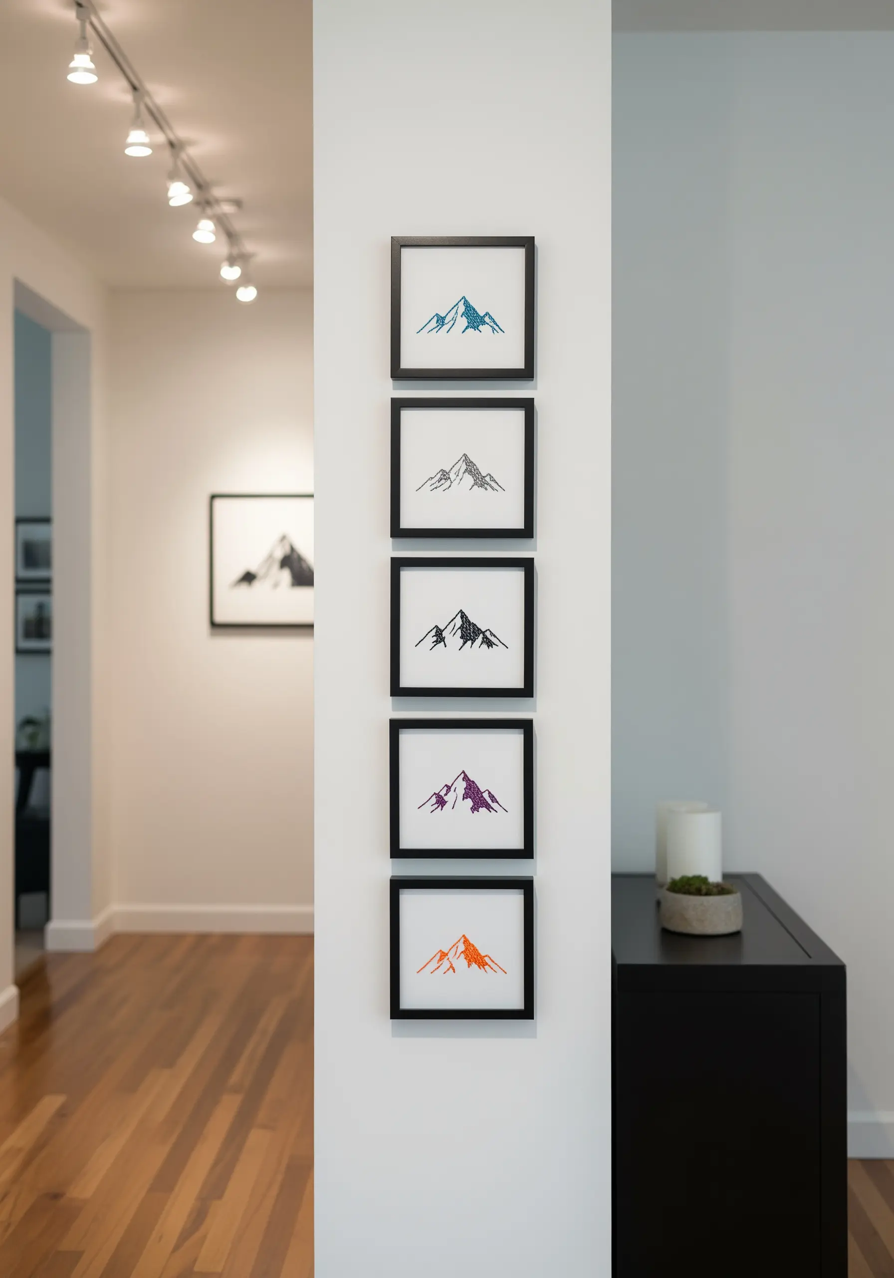 A vertical series of five small framed embroideries, each showing a minimalist mountain outline.