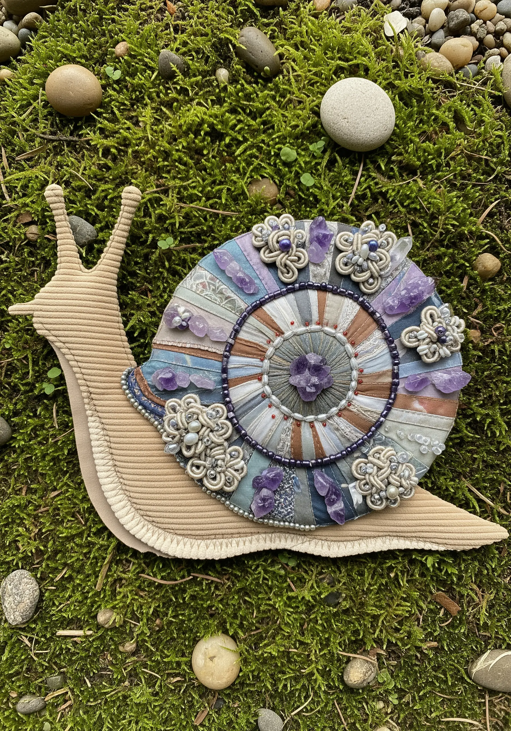 Fabric collage snail with a heavily embellished shell using beads and crystals.