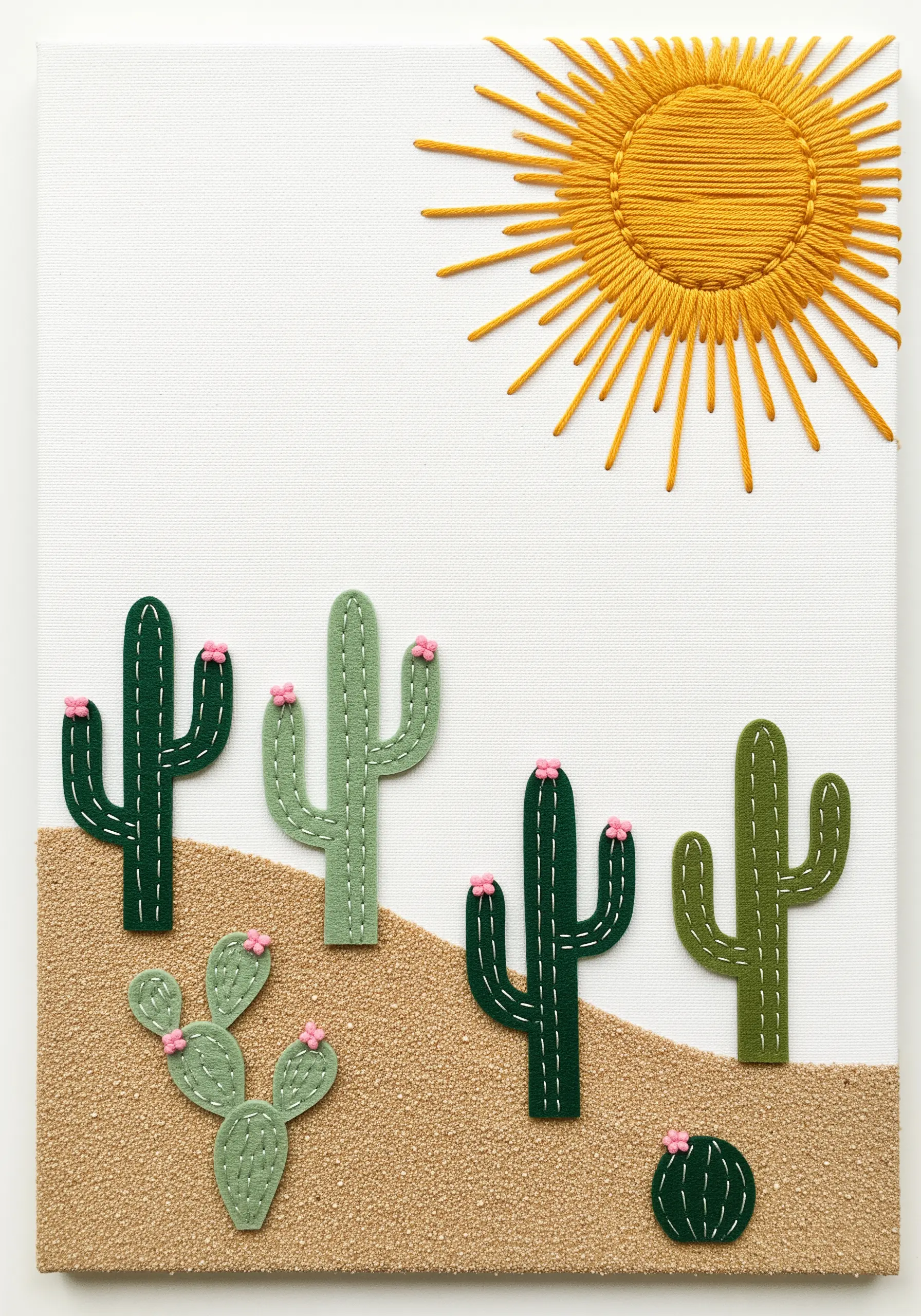 A minimalist desert scene on canvas featuring felt cacti and a large, satin-stitched yellow sun.