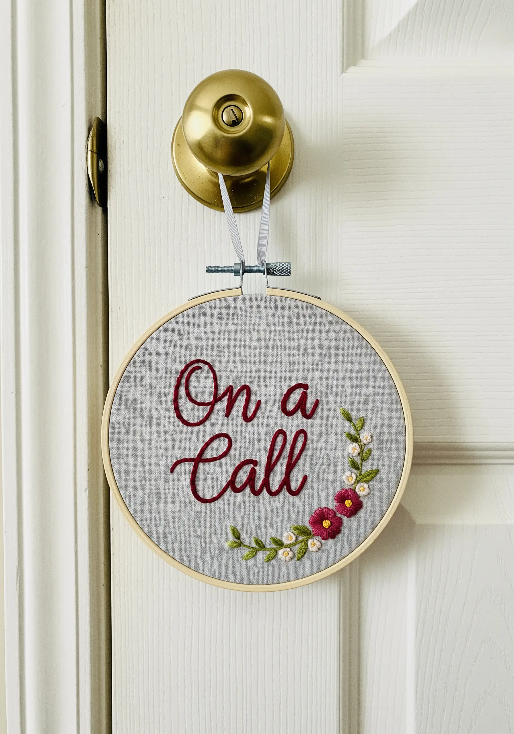An embroidery hoop door hanger with 'On a Call' stitched in cursive.